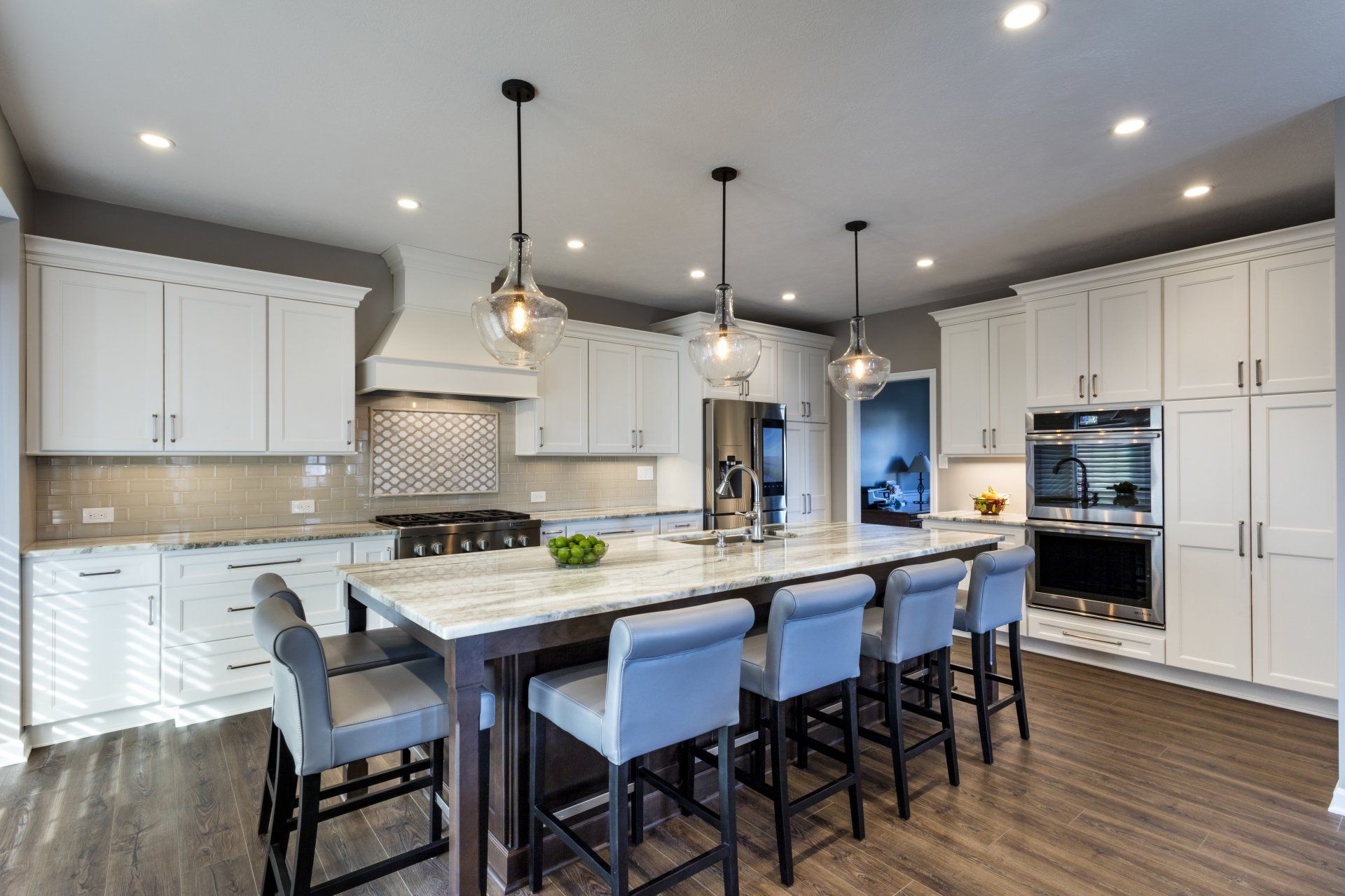 Bright modern kitchen with white cabinets, large island, pendant lights, and bar stools