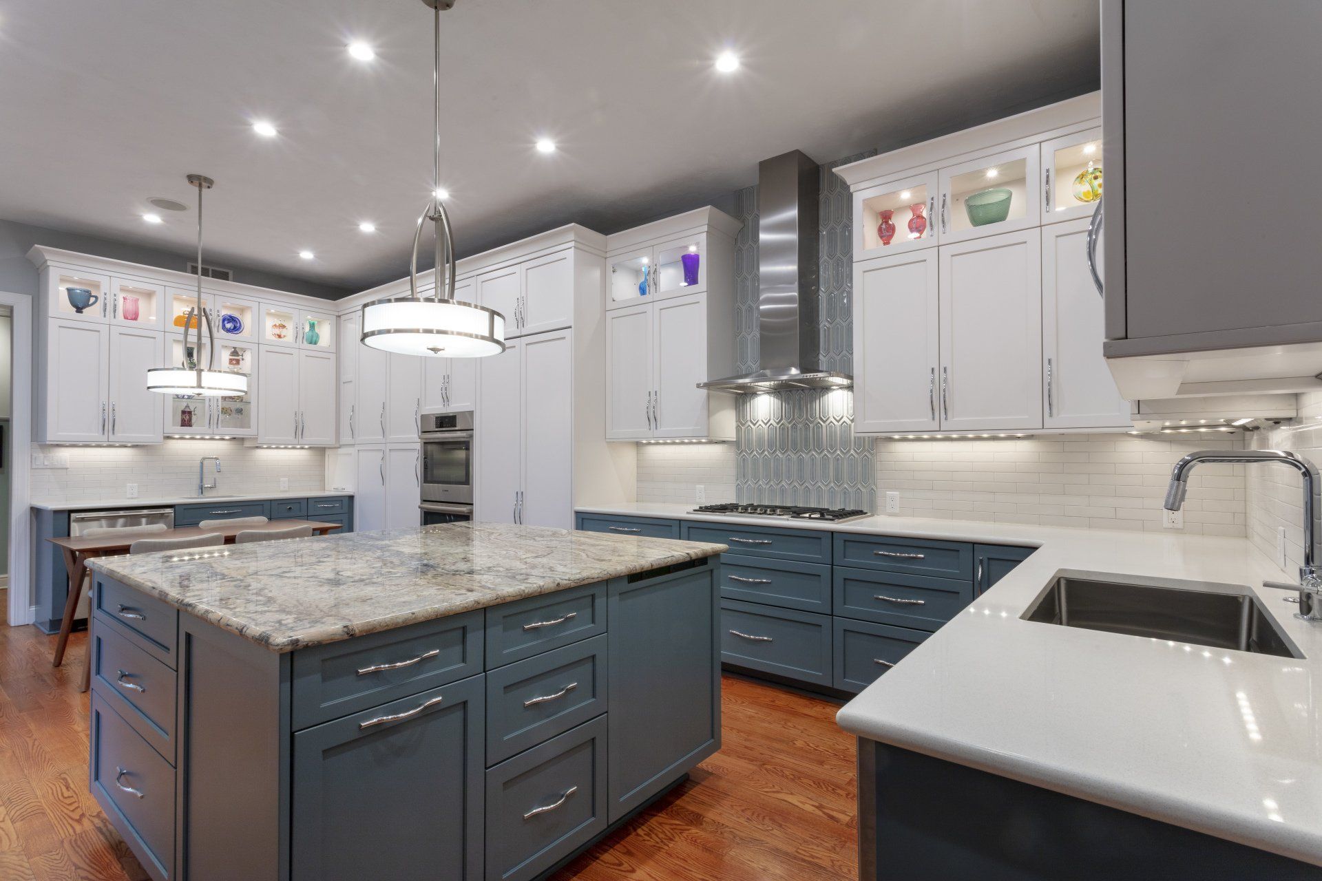 Modern kitchen with white cabinets, blue island, granite counters, and stainless steel appliances