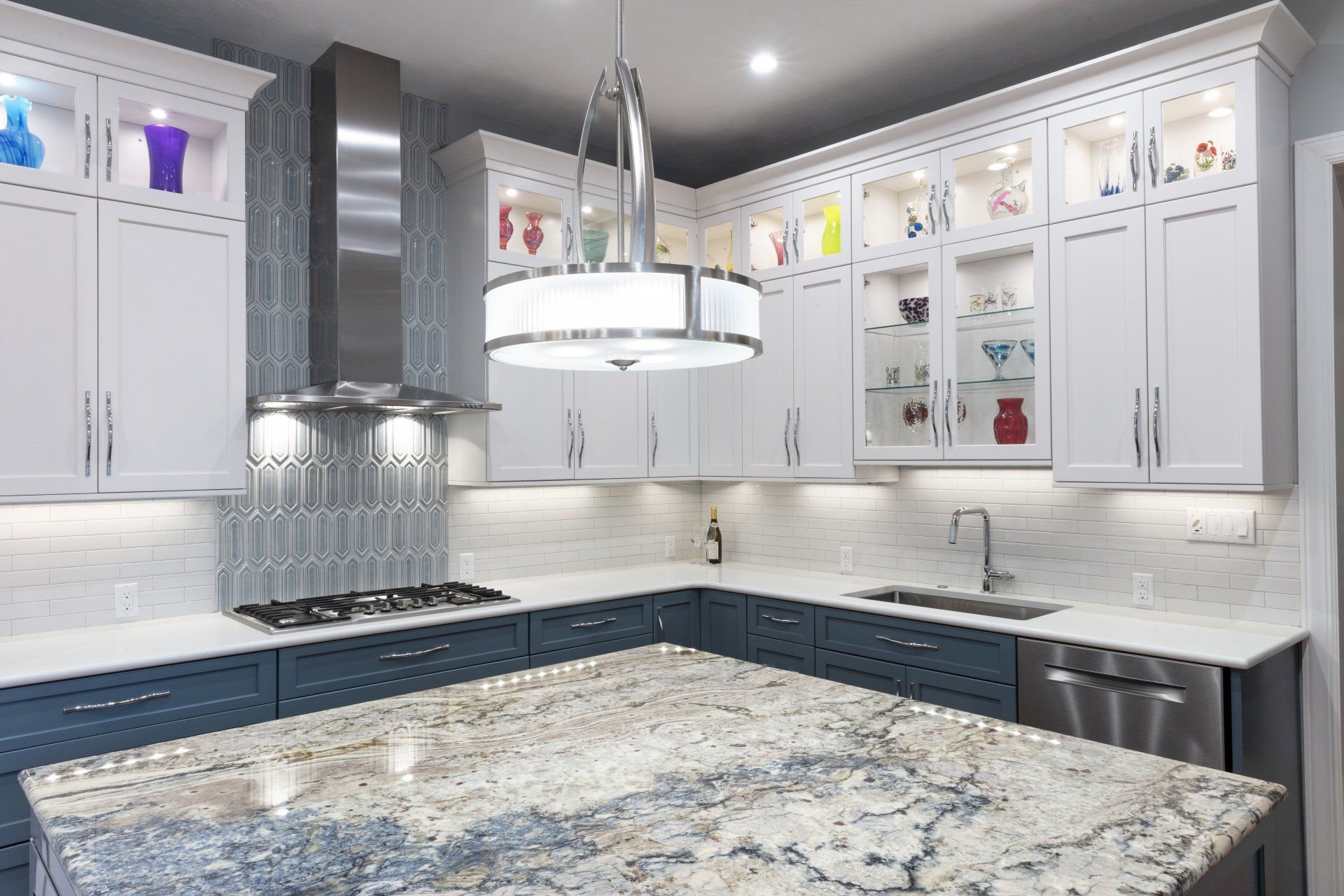 Bright modern white kitchen with marble island, glass-front cabinets, and stainless steel hood