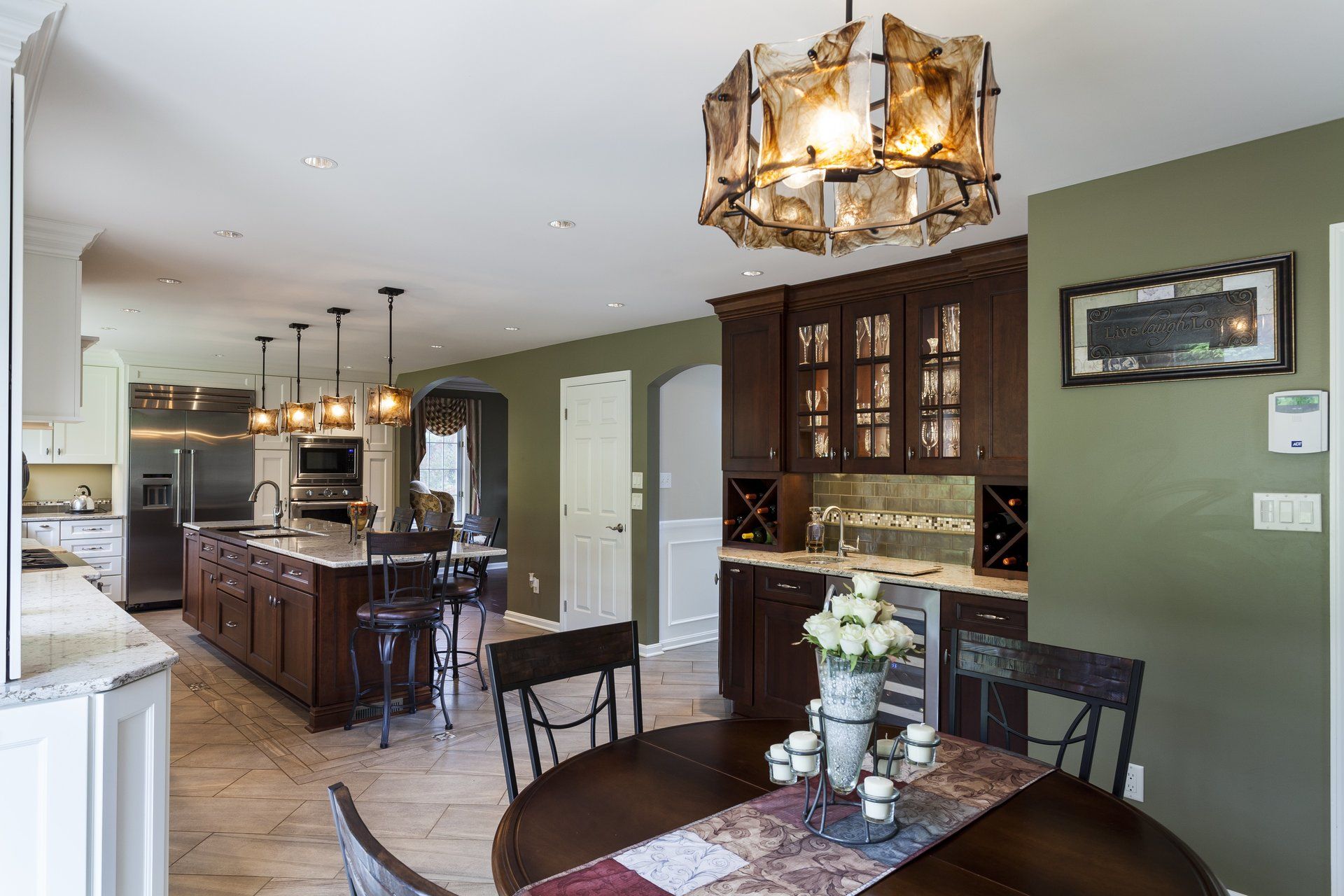 Open kitchen and dining area with dark wood cabinets, green walls, and hanging pendant lights