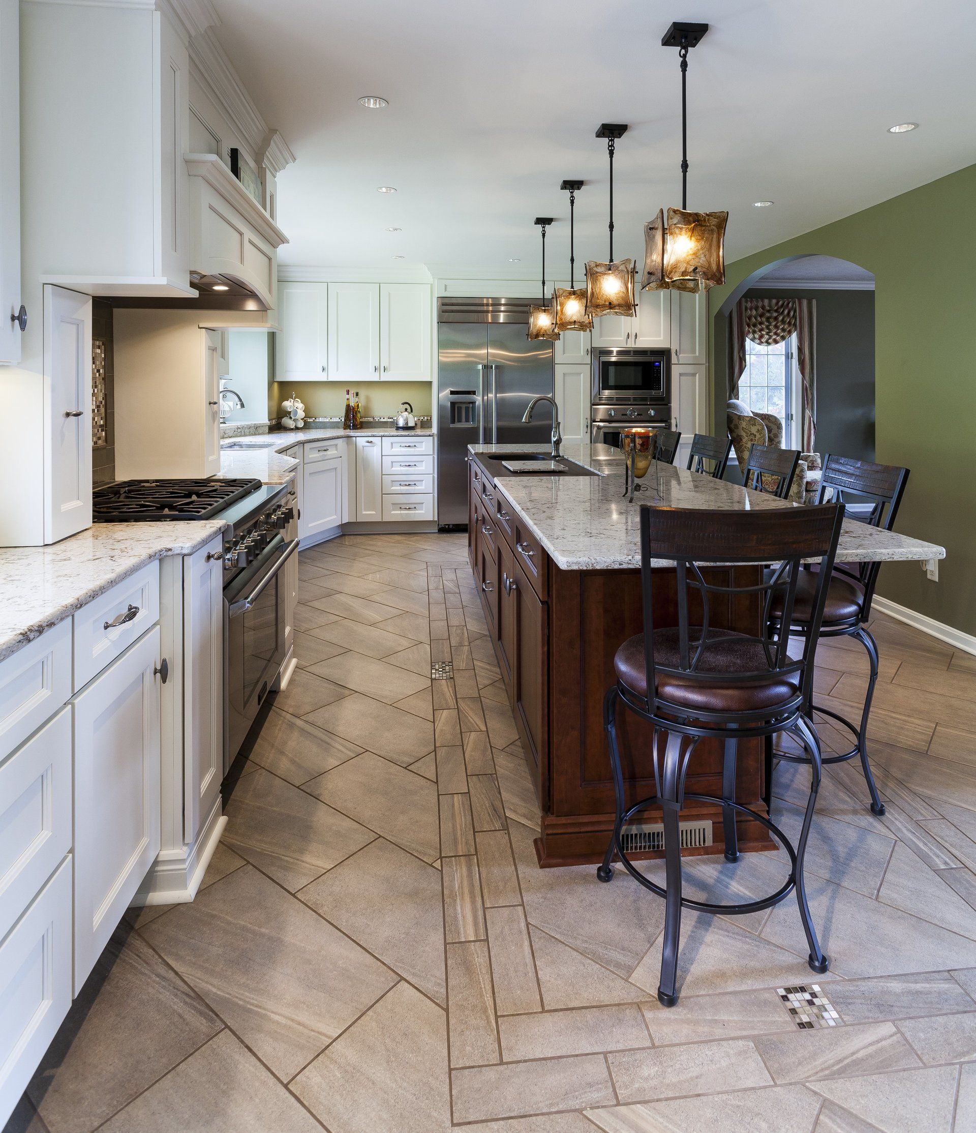 Modern kitchen with white cabinets, granite island, pendant lights, and barstools on a patterned tile floor