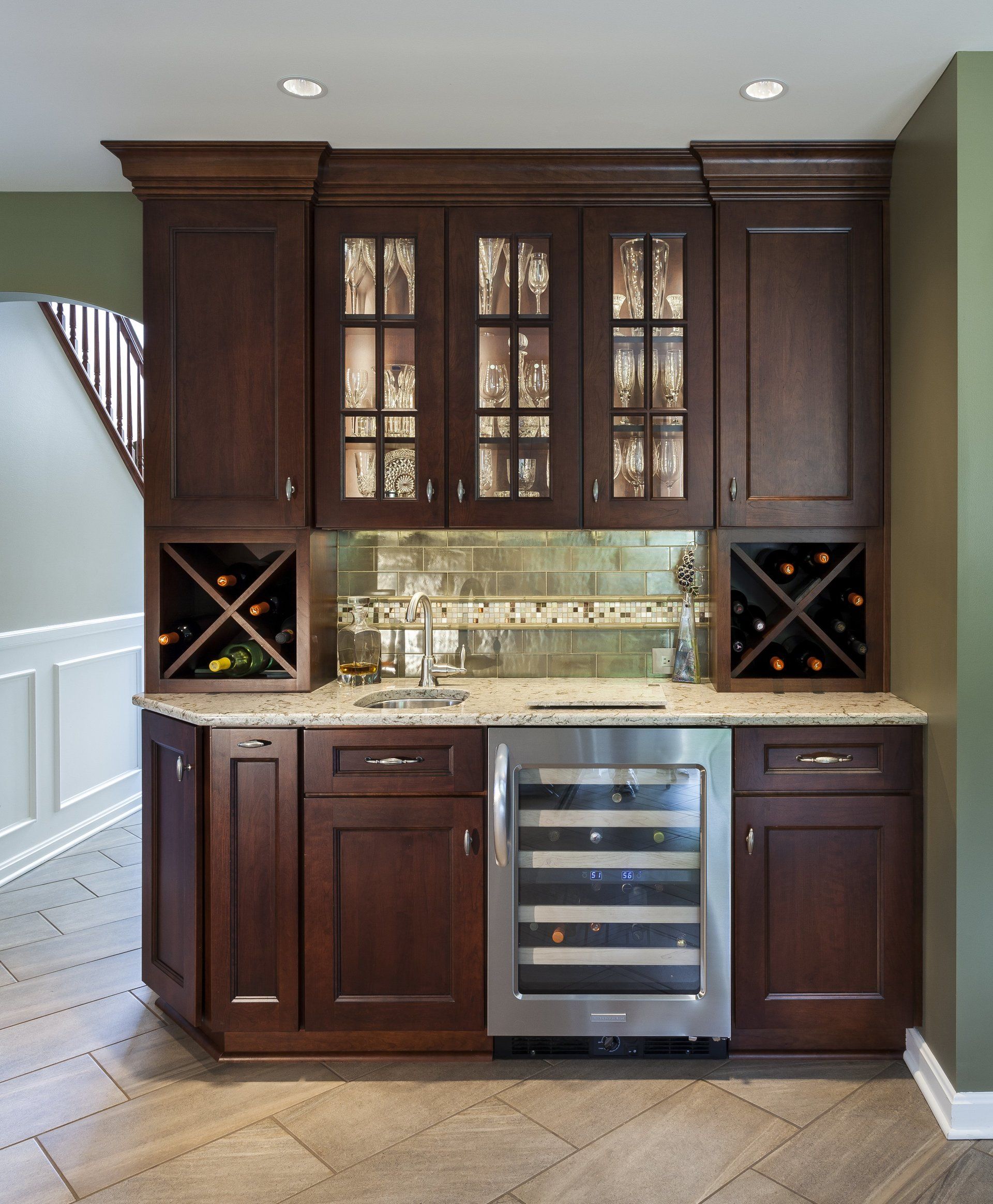 Dark wood home wet bar with wine cubbies, glass cabinets, granite counter, and built-in wine fridge.