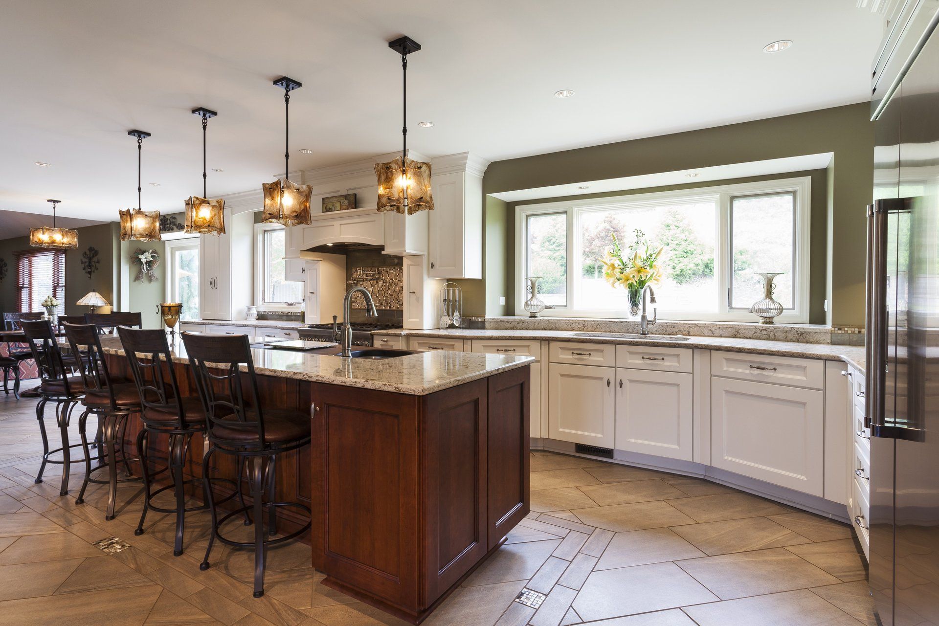 Bright kitchen with island, pendant lights, white cabinets, and large window over a sink