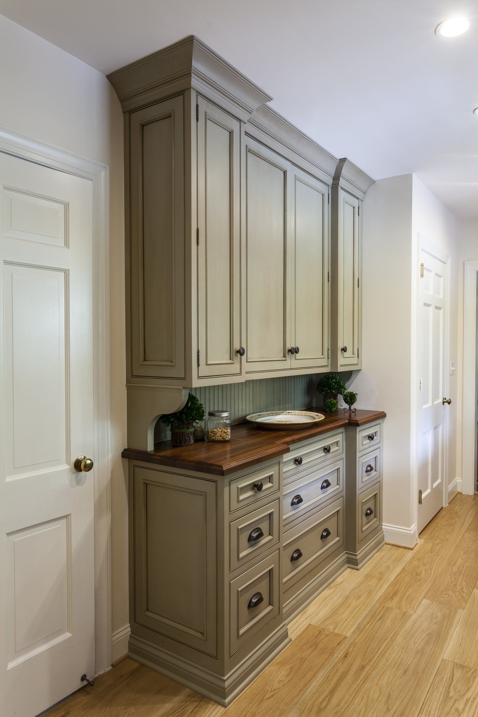 Built-in beige cabinetry with wood countertop in a narrow hallway kitchen nook