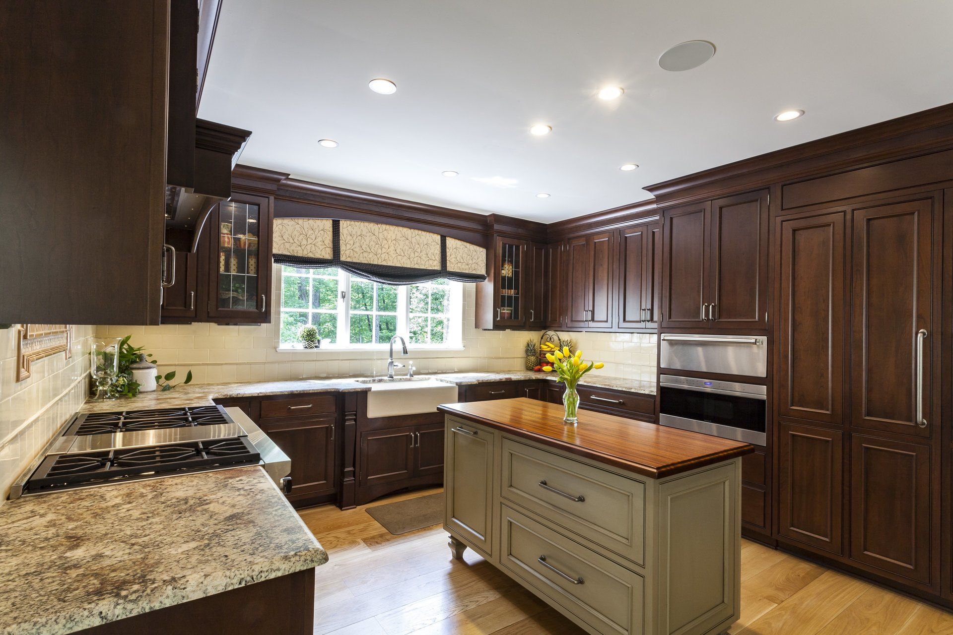 Modern kitchen with dark wood cabinets, granite counters, and a central island under bright recessed lights