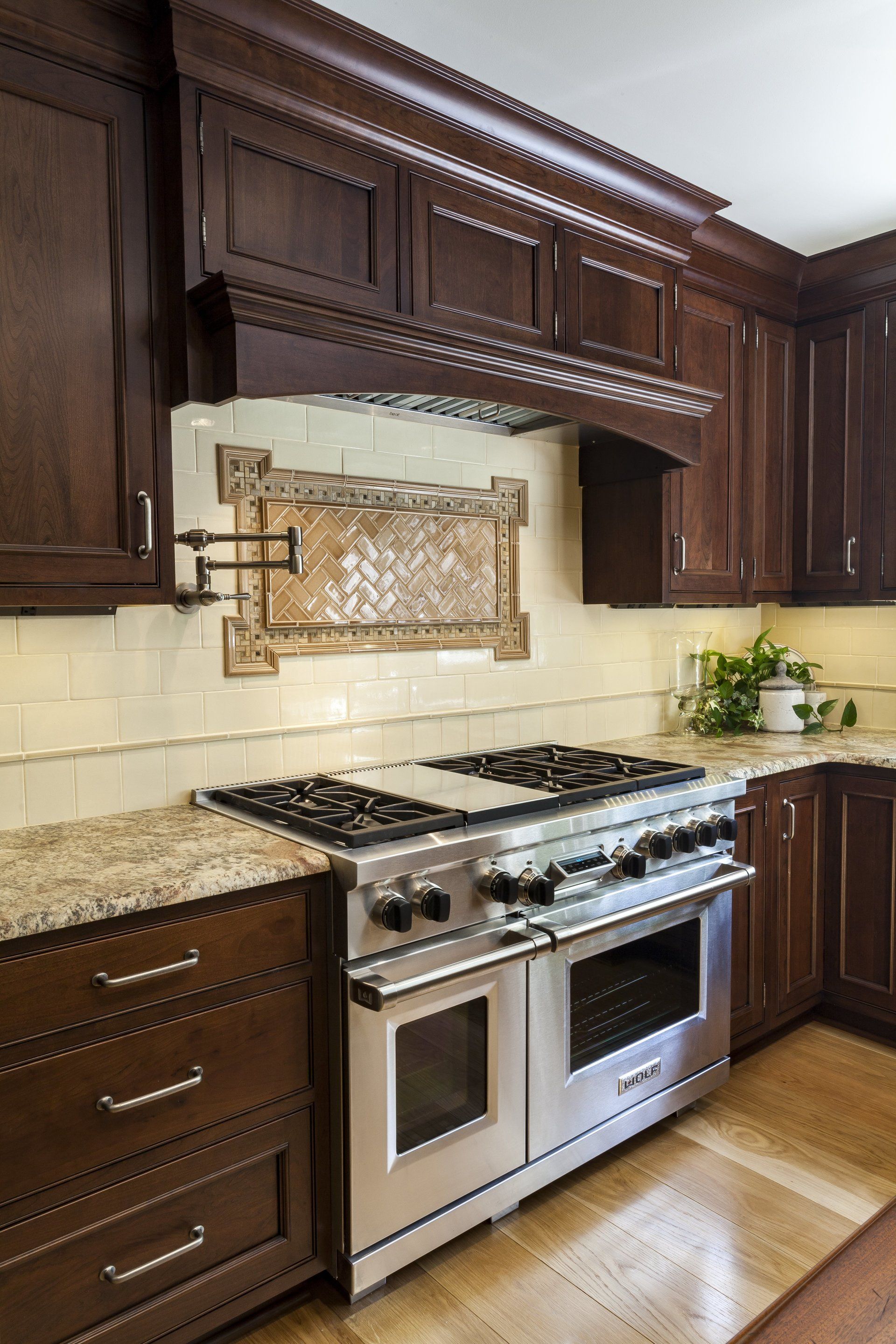 Modern kitchen with dark wood cabinets, beige tile backsplash, and stainless steel gas range and oven.