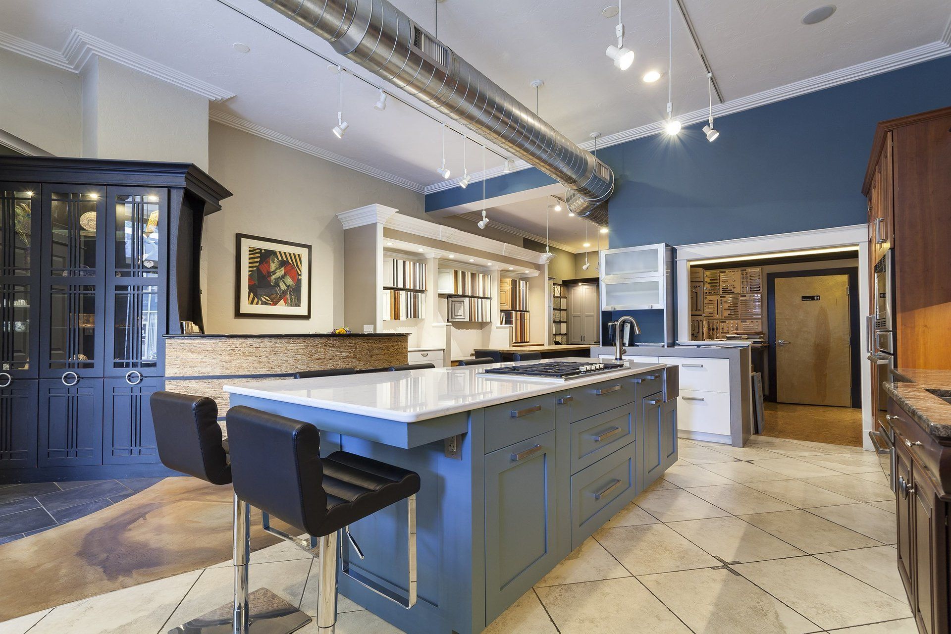 Modern kitchen with large island, blue cabinetry, pendant lights, and tiled floor