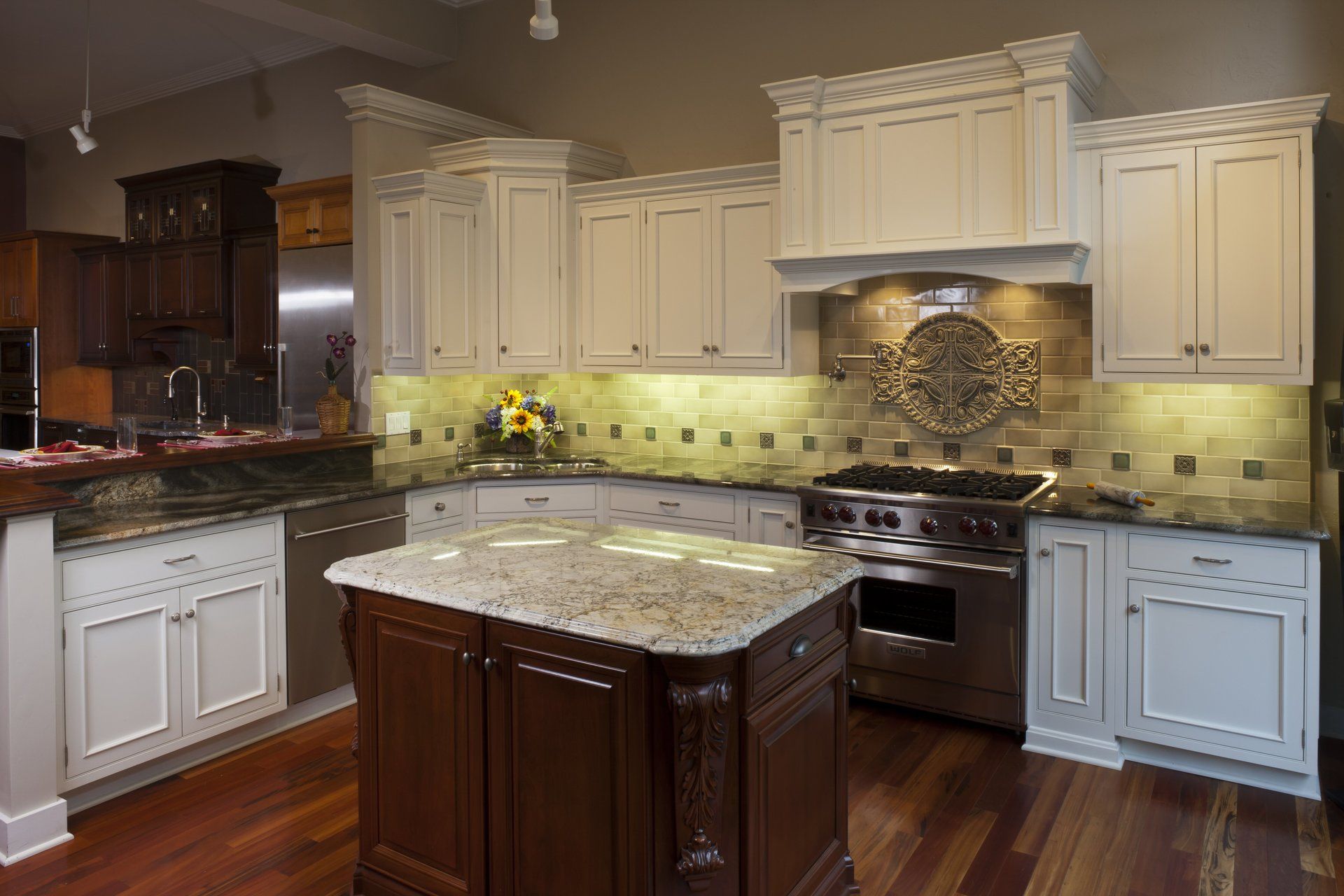 Elegant kitchen with cream cabinets, granite island, stainless steel appliances, and warm wood floors