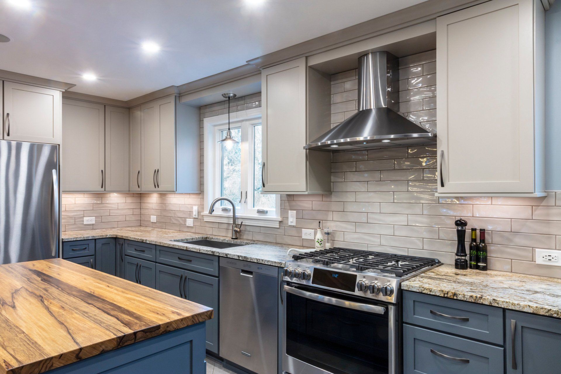 Modern kitchen with gray cabinets, stainless steel appliances, tiled backsplash, and butcher-block island.