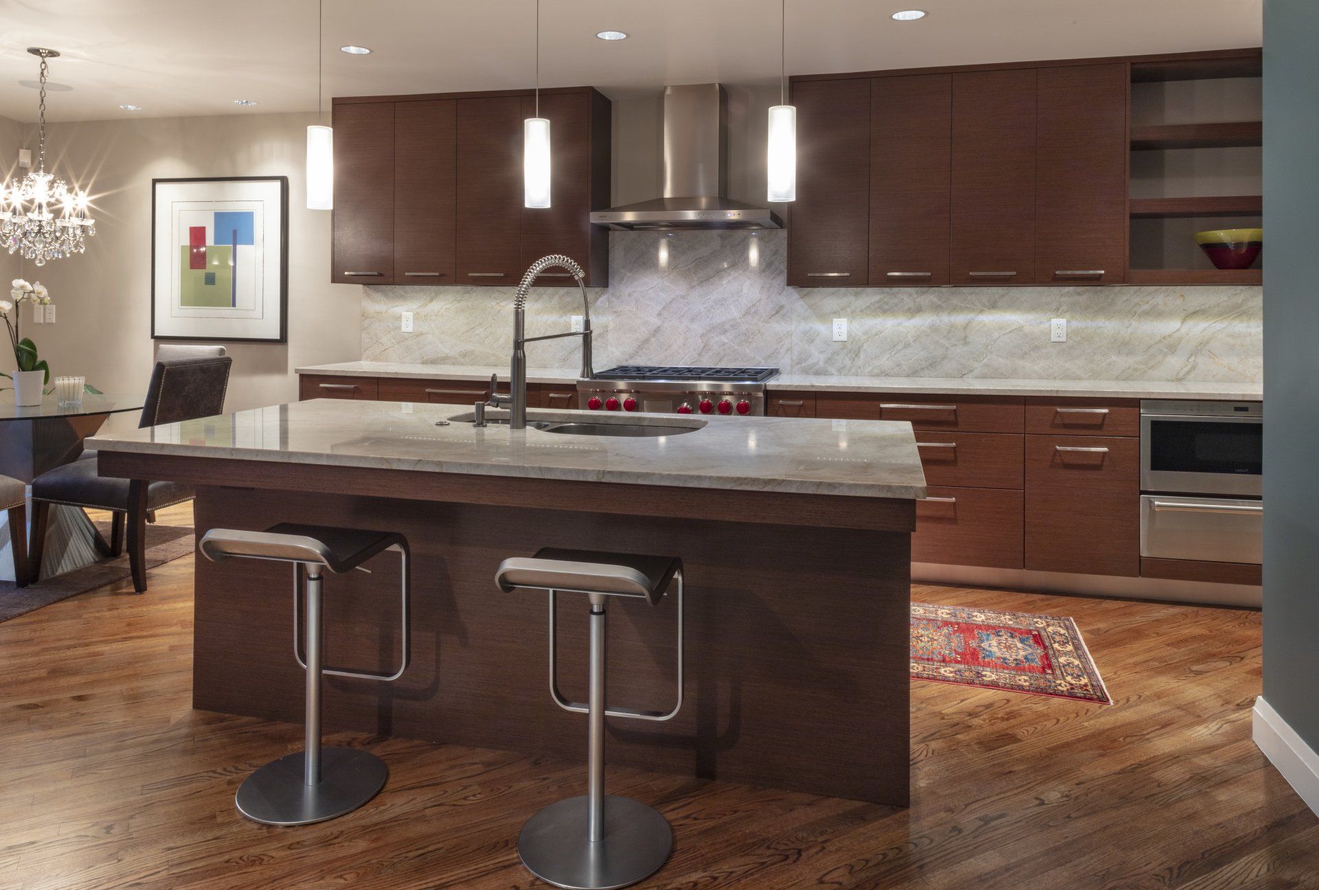 Modern kitchen with dark wood cabinets, granite island, bar stools, and stainless steel appliances