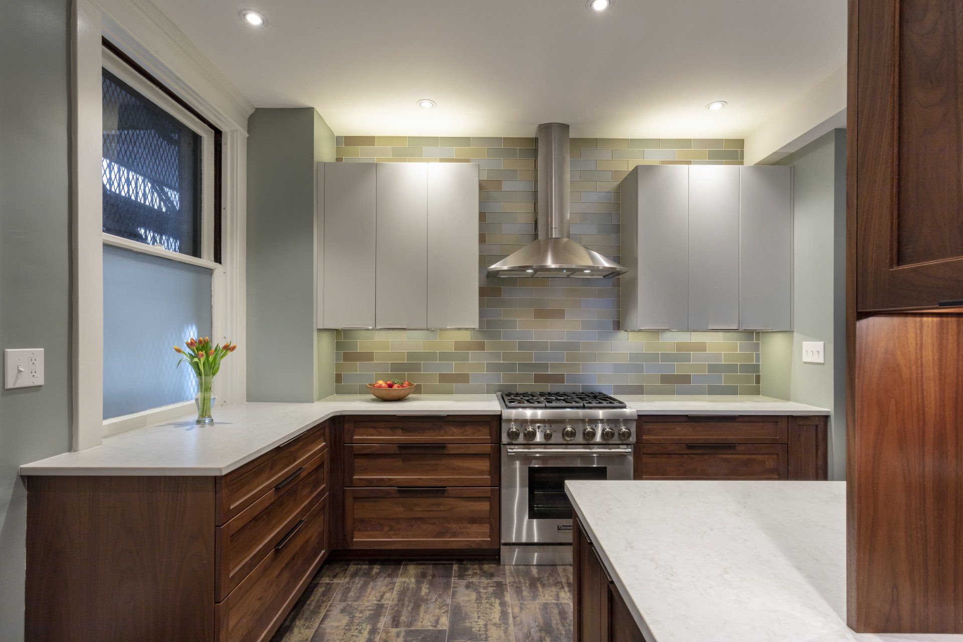 Modern kitchen with gray cabinets, stainless steel range hood, and light countertops