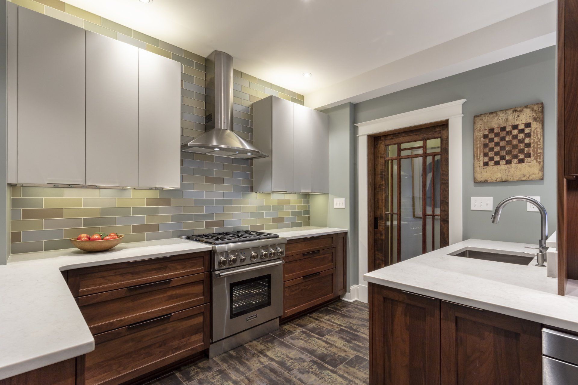 Modern kitchen with gray cabinets, stainless stove, white countertops, and wood island and sink cabinet