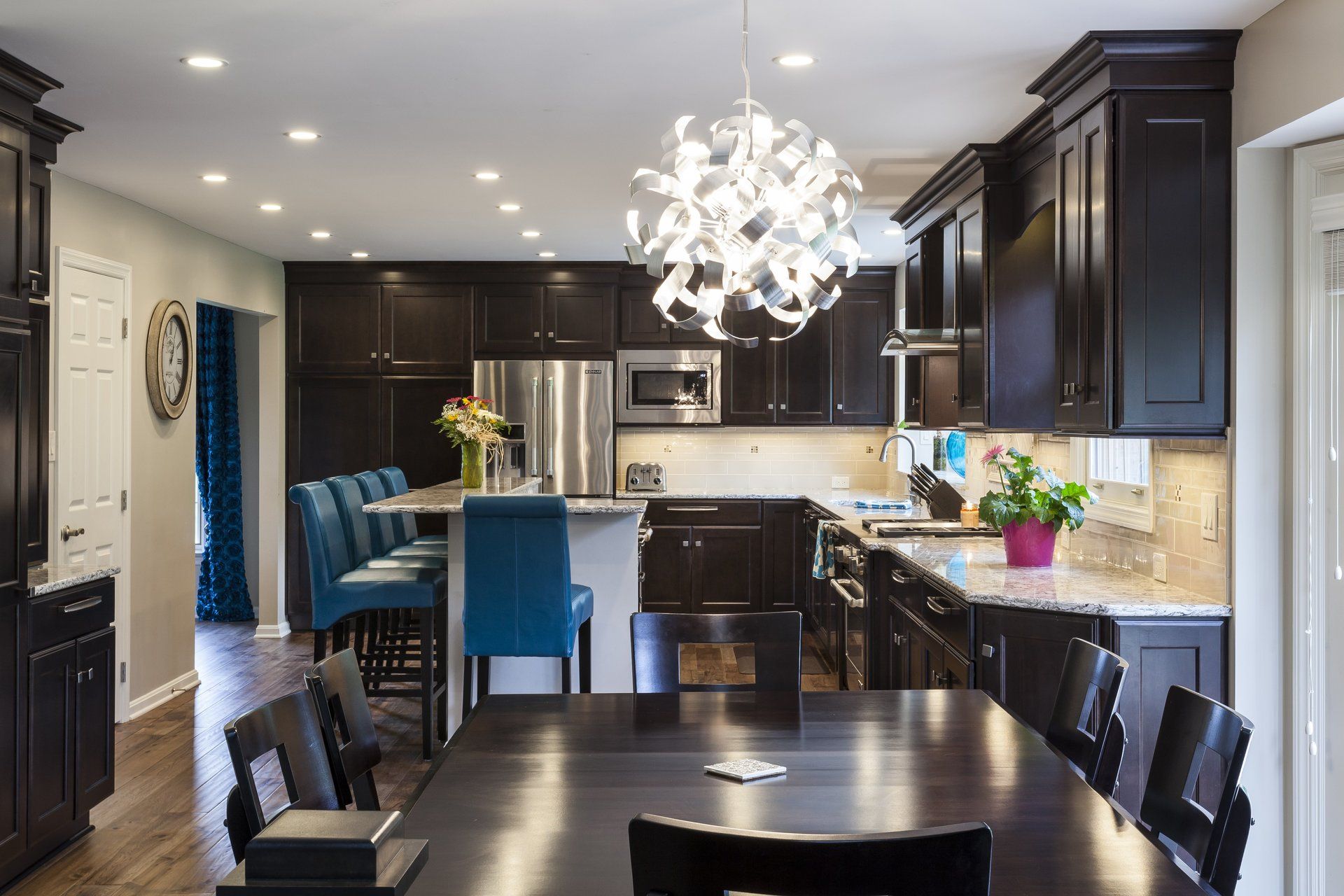 Modern kitchen with dark cabinets, blue bar stools, pendant light, and dining table