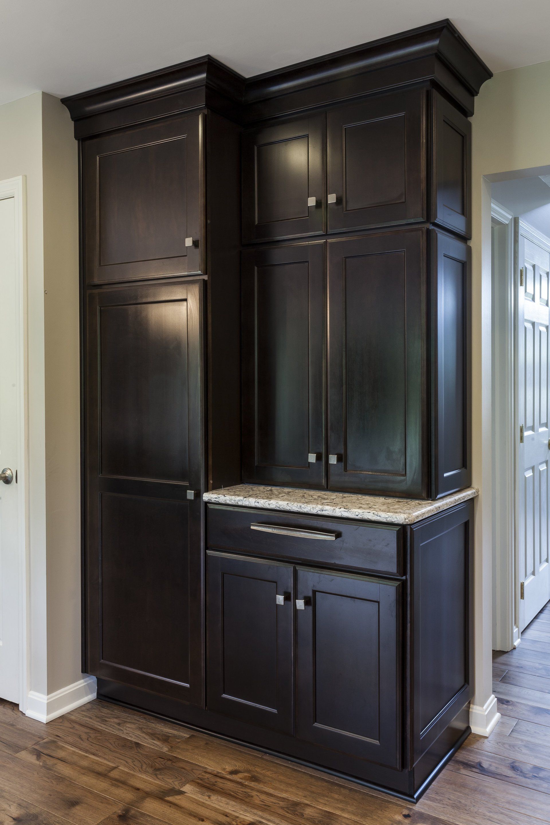 Dark wood kitchen cabinet with upper and lower storage, granite countertop, in a home hallway area