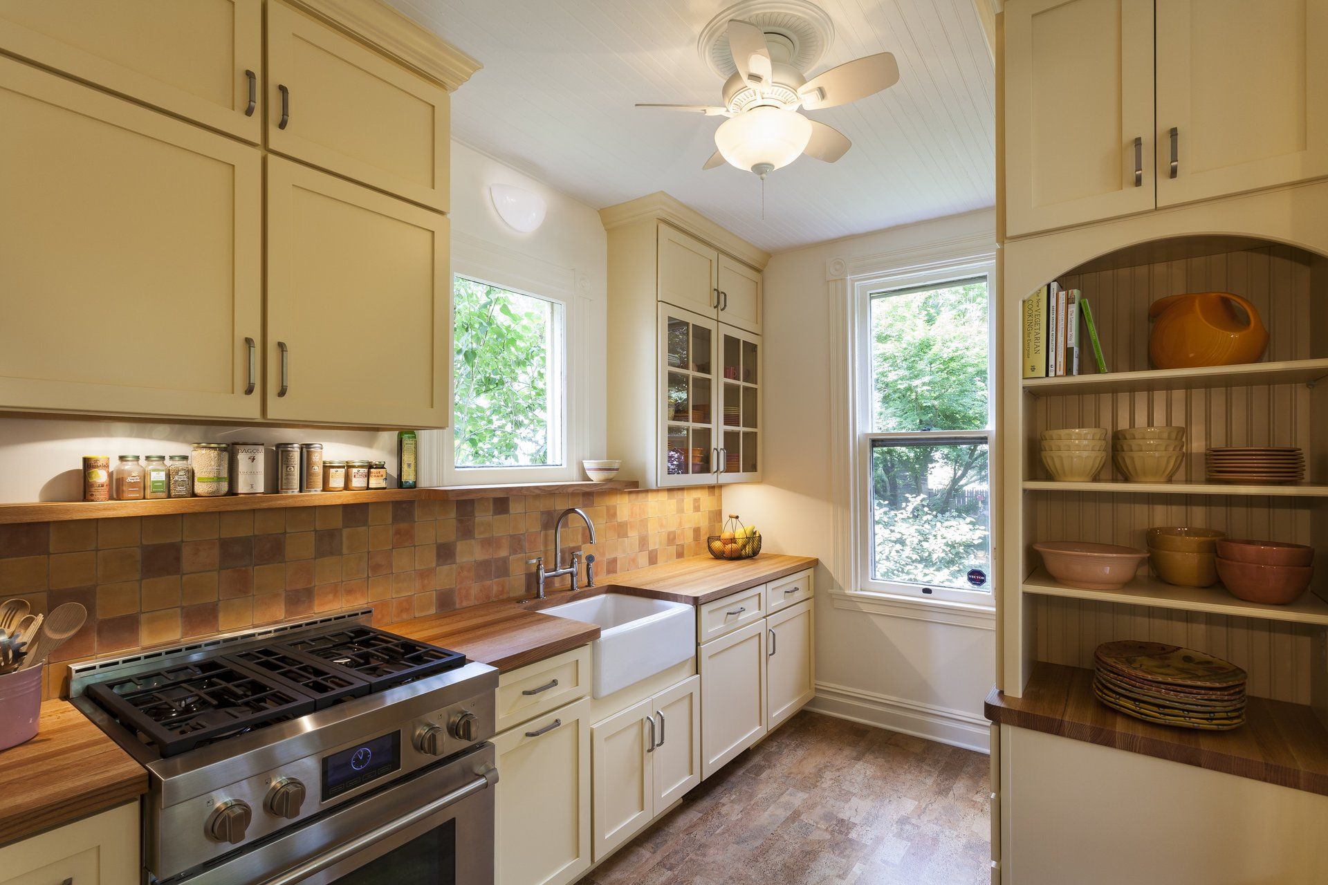 Bright kitchen with cream cabinets, gas stove, farmhouse sink, and sunlit windows