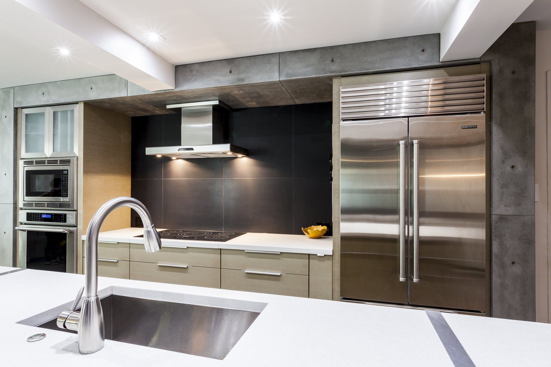 Modern kitchen with stainless steel appliances, white island, and black backsplash