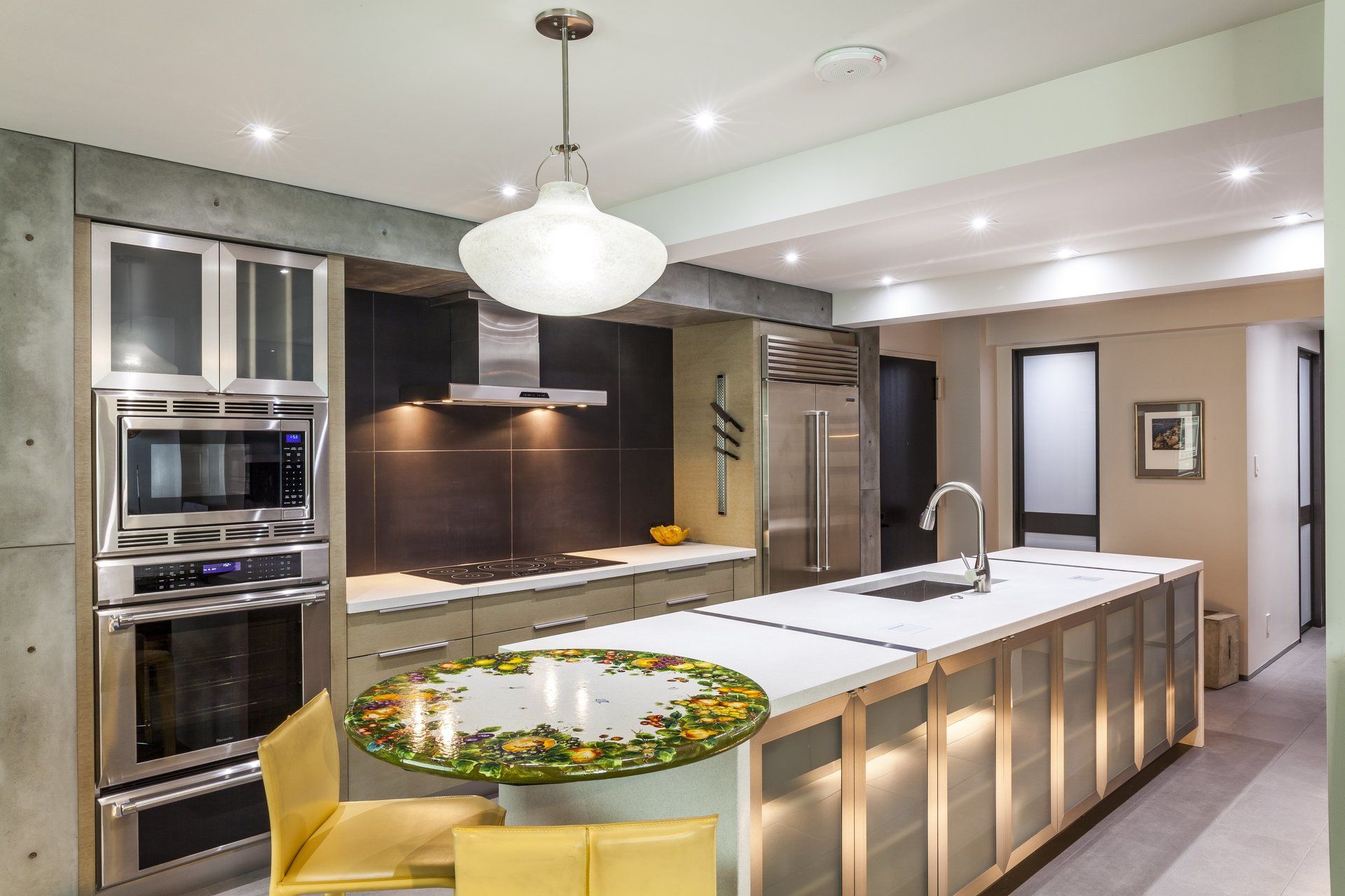 Modern kitchen with large island, pendant light, stainless appliances, and beige cabinetry