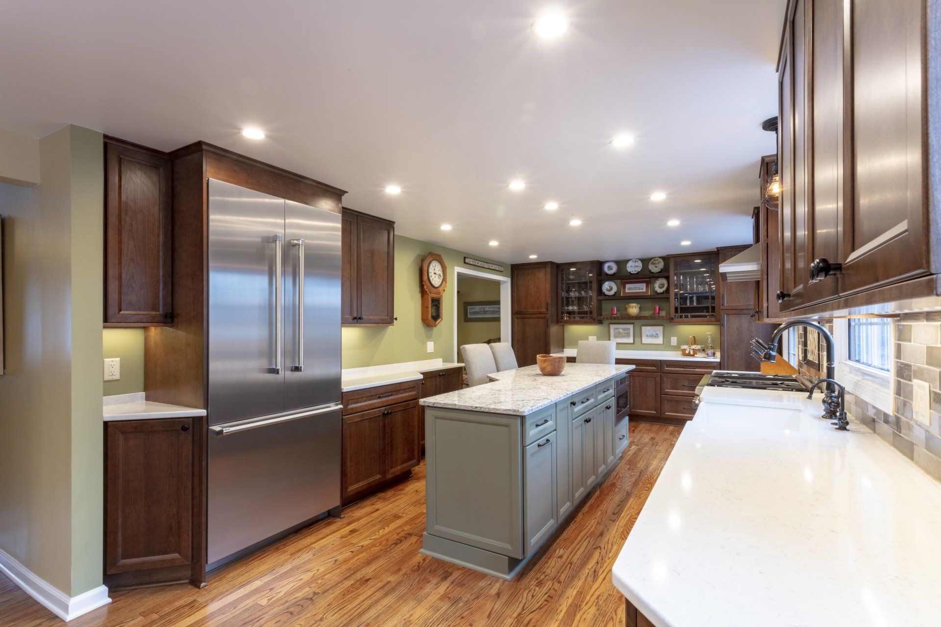 Modern kitchen with stainless steel fridge, dark wood cabinets, white countertops, and center island