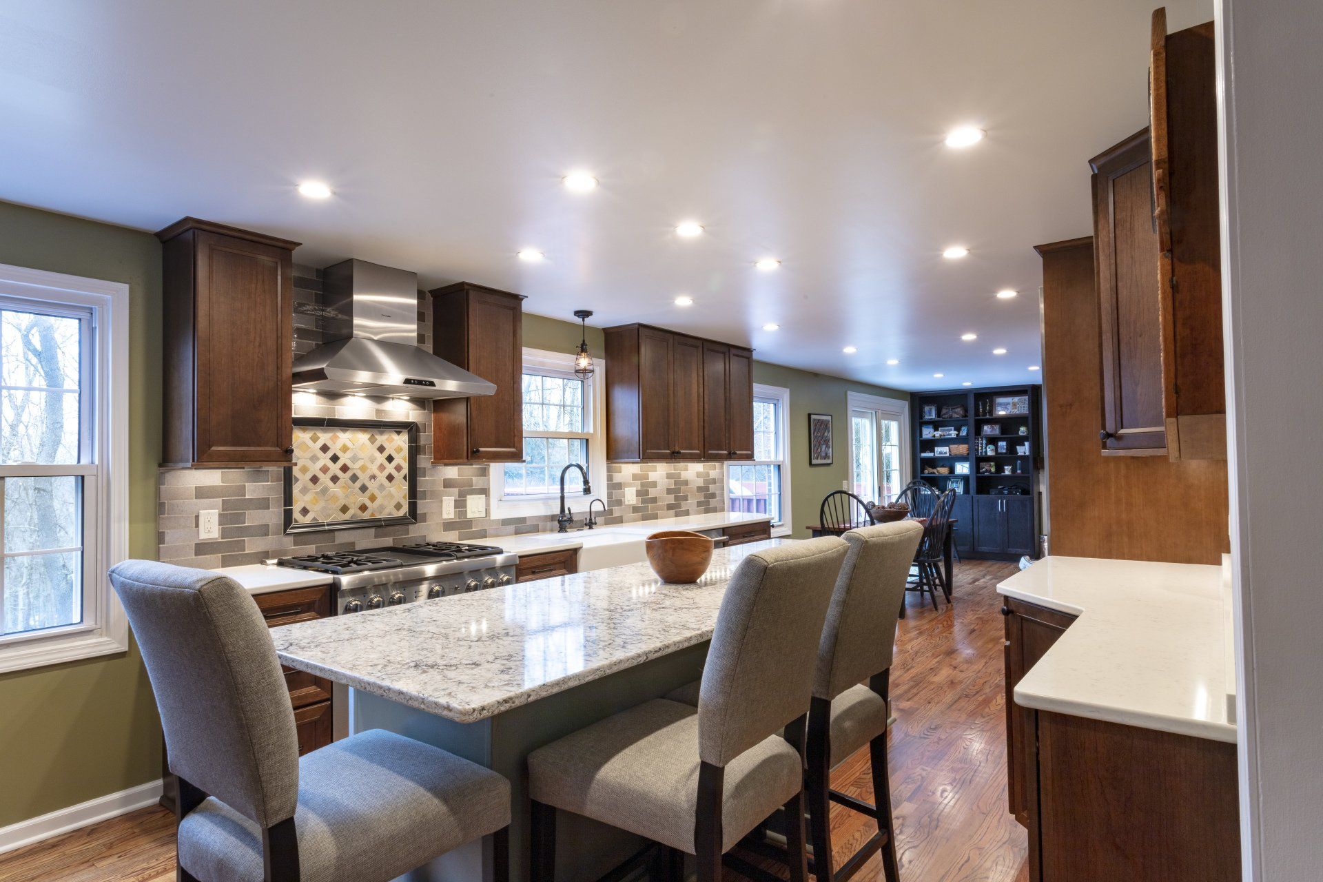 Modern kitchen with granite island, barstools, wood cabinets, and stainless steel appliances