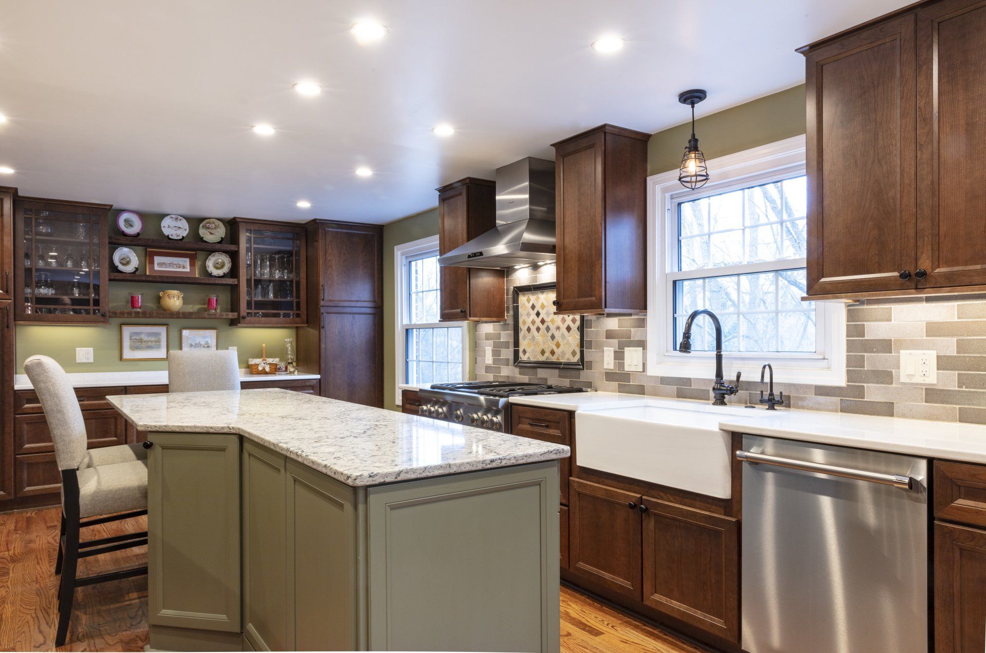 Modern kitchen with dark wood cabinets, granite island, stainless appliances, and a window over the sink