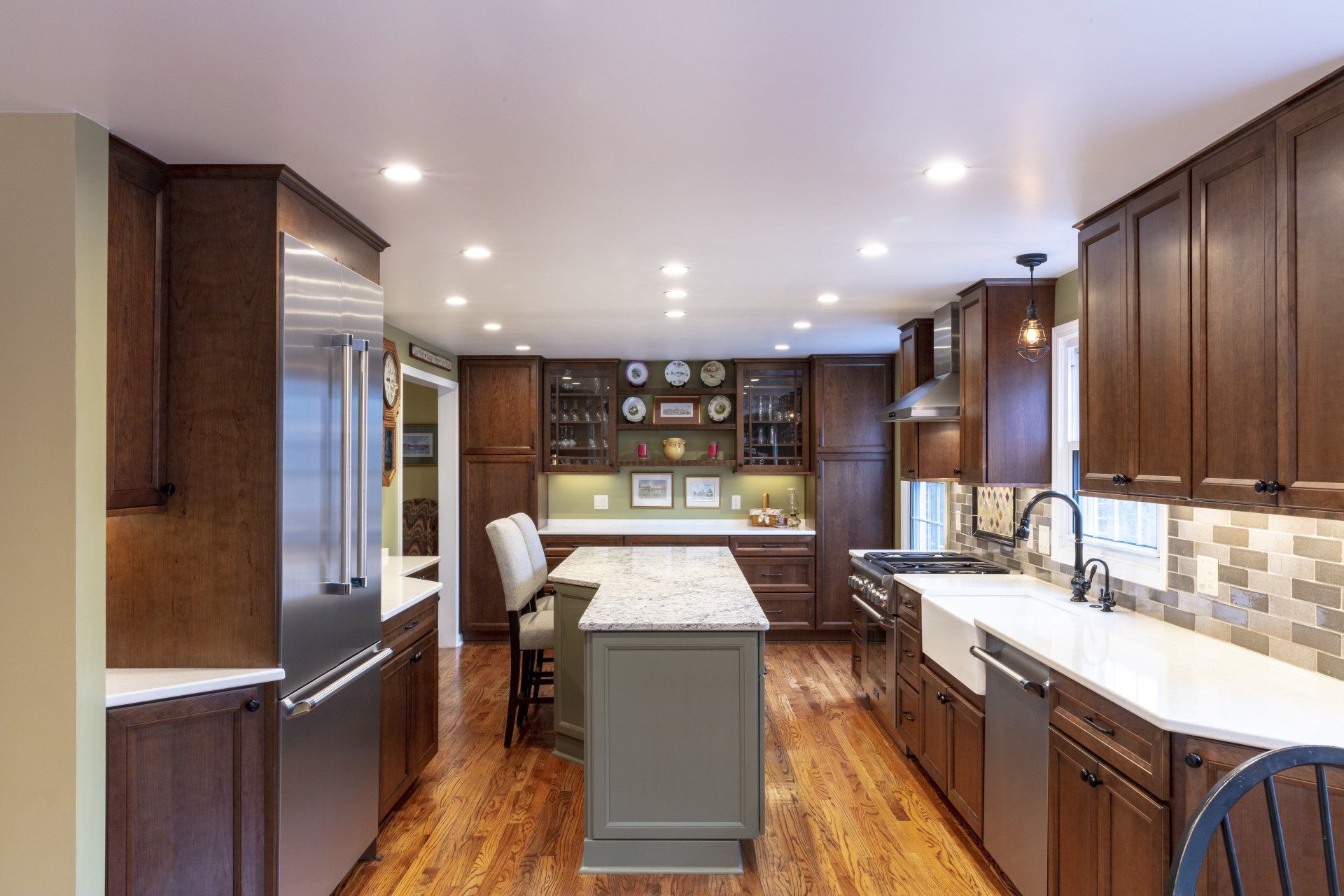 Modern kitchen with dark wood cabinets, white countertops, stainless appliances, and a central island