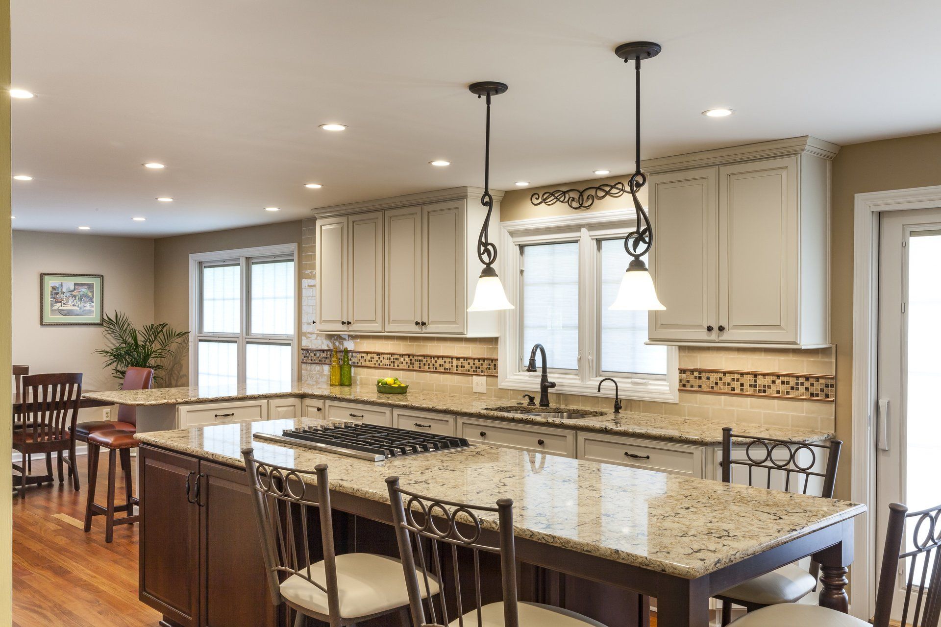 A kitchen with white cabinets , granite counter tops , a table and chairs.