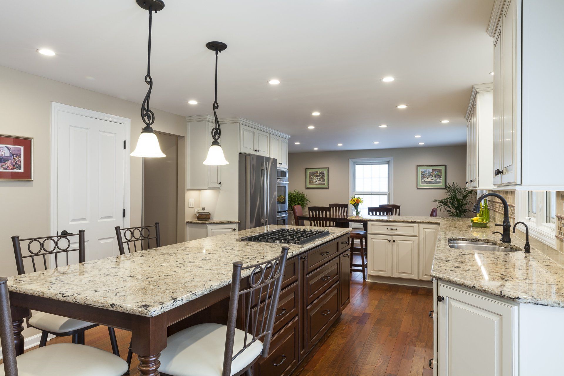 Bright kitchen with granite island, pendant lights, white cabinets, and hardwood floors