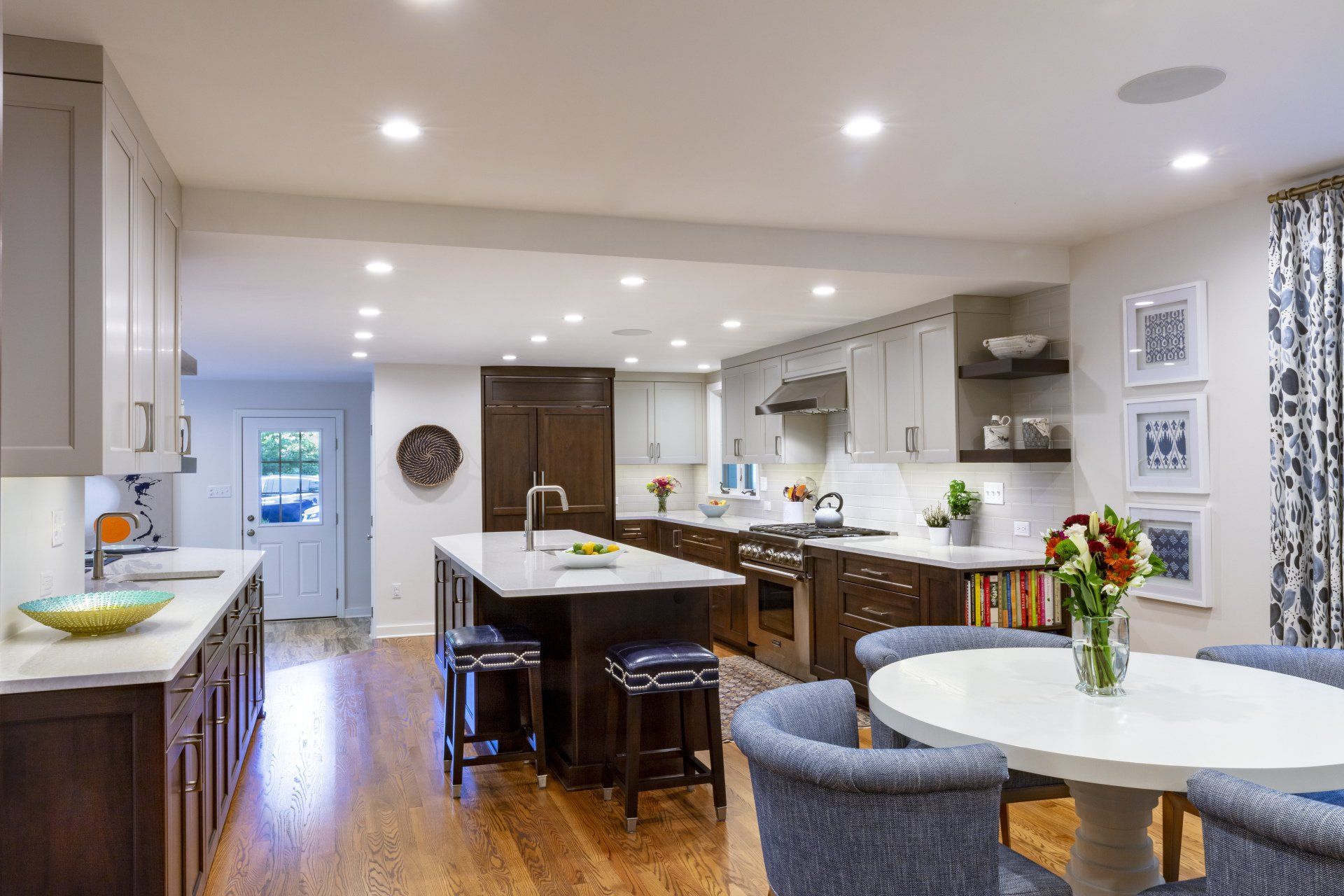 Bright modern kitchen with island, barstools, round table, and recessed ceiling lights