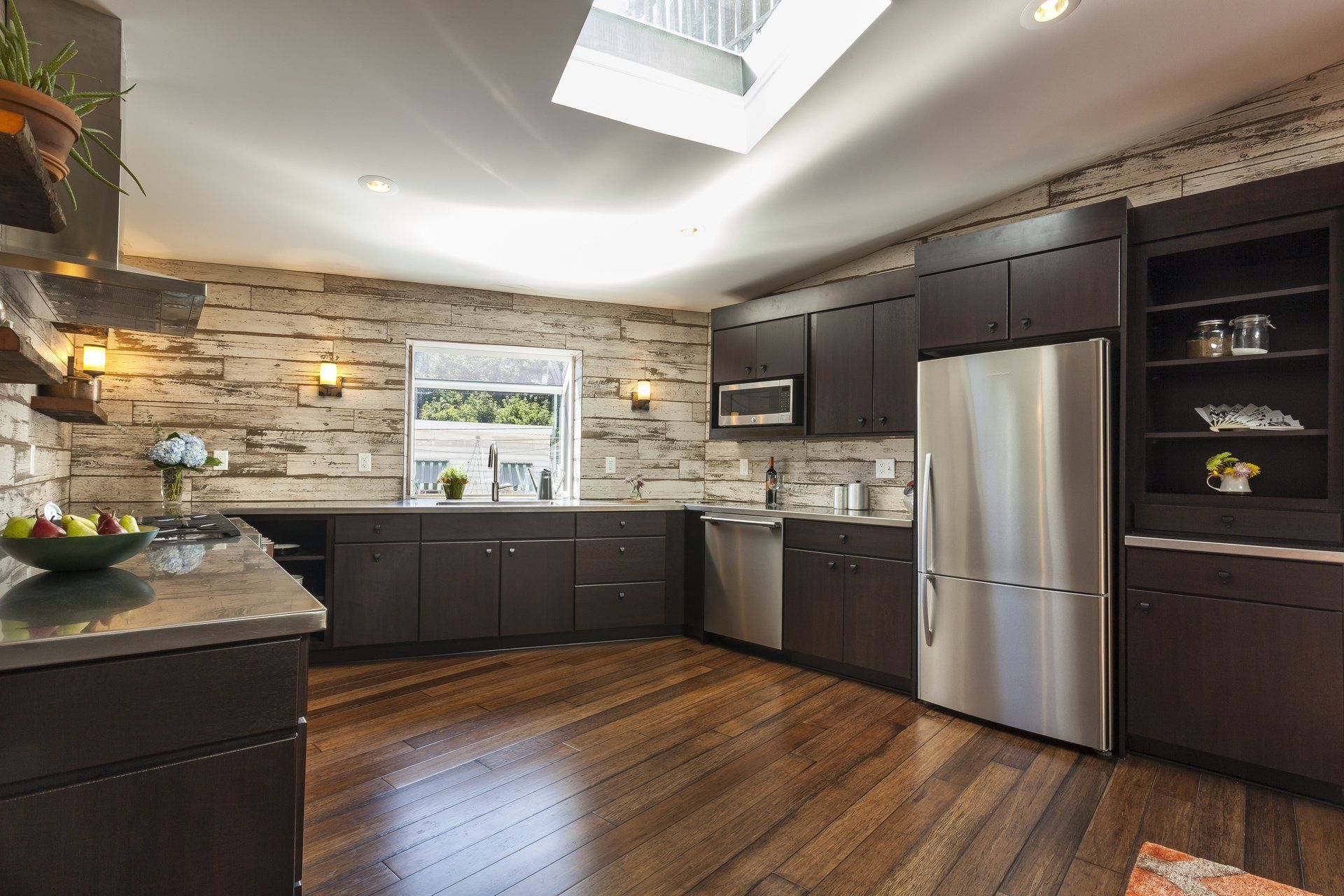 Modern kitchen with dark cabinets, stainless steel refrigerator, stone backsplash, and hardwood floors