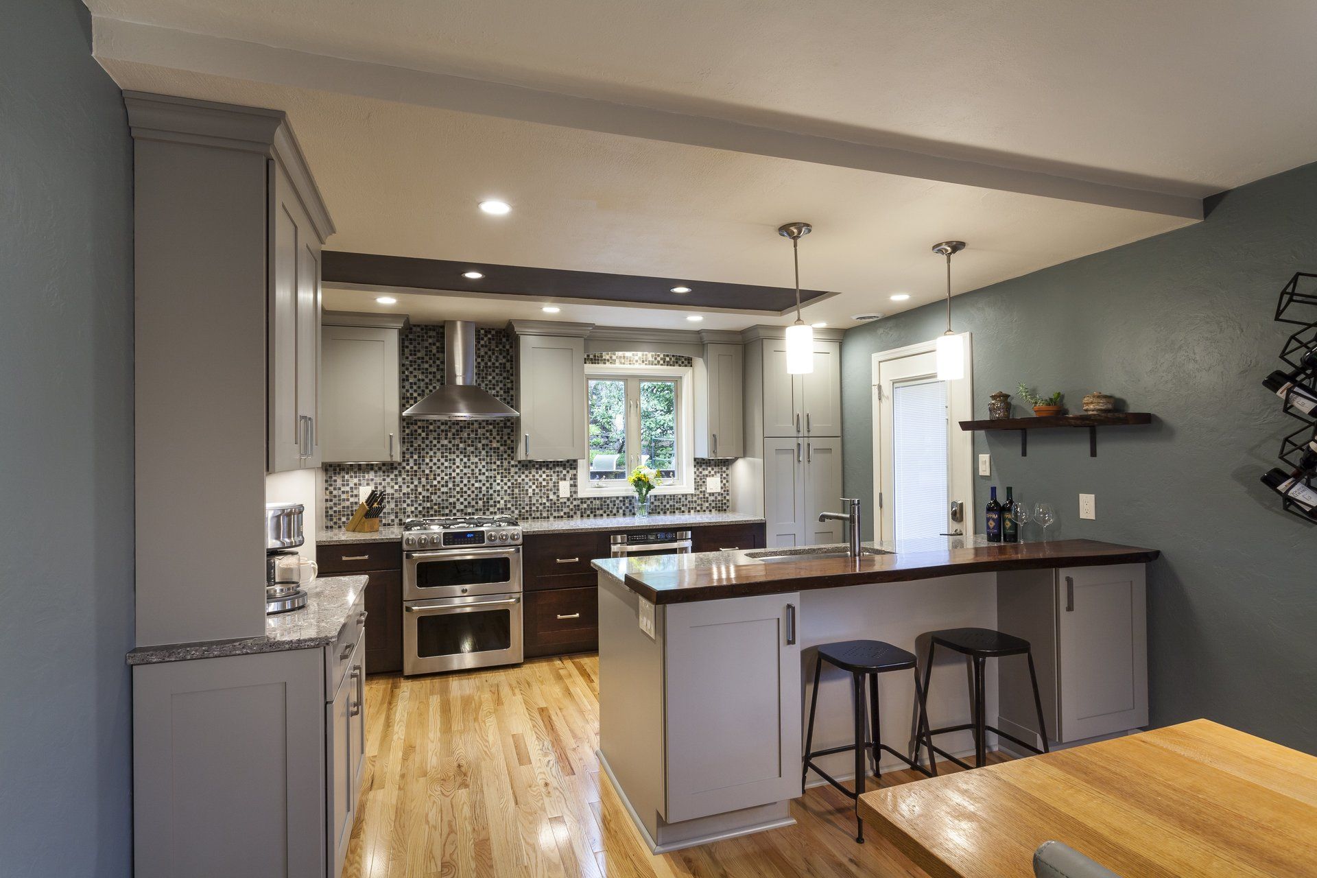 Modern kitchen with gray cabinets, white island, pendant lights, and wood floors