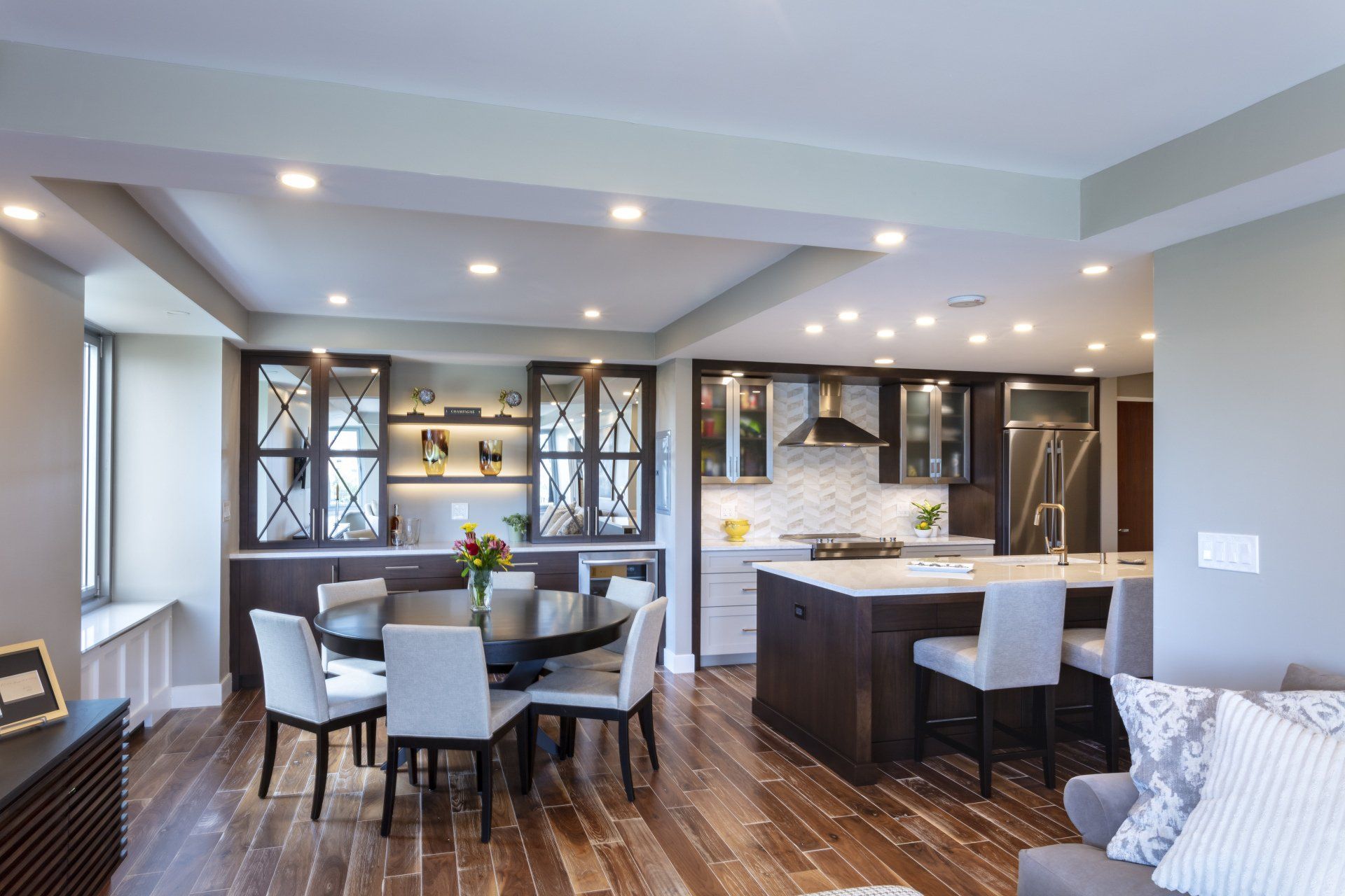 Modern open-concept dining and kitchen area with dark wood floors, gray walls, and recessed lighting