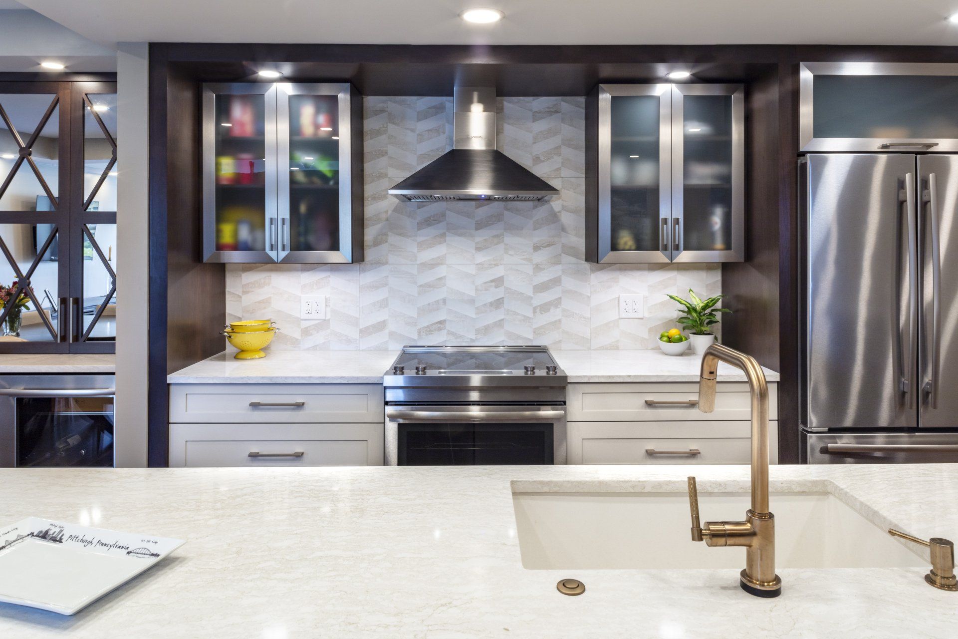 Modern kitchen with stainless steel appliances, white countertops, gray cabinets, and a central island sink