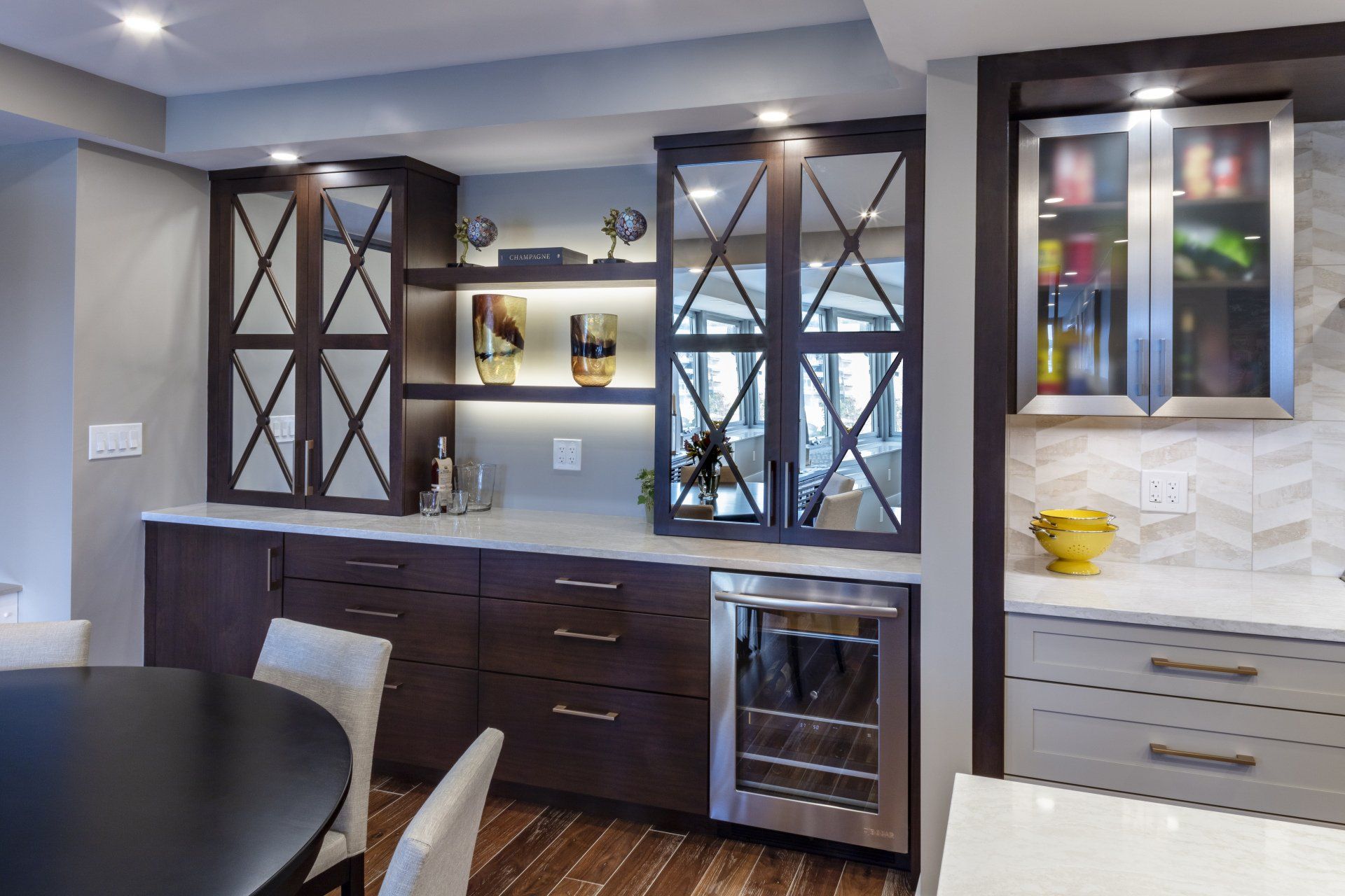 Modern kitchen with dark cabinets, glass-front shelves, and white tile backsplash