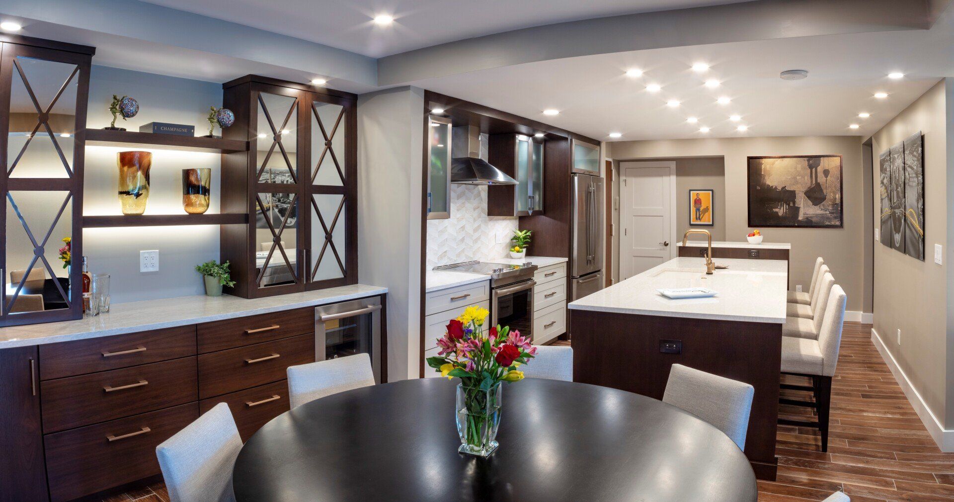 Modern kitchen with island, white cabinetry, dark wood accents, and a round dining table in the foreground