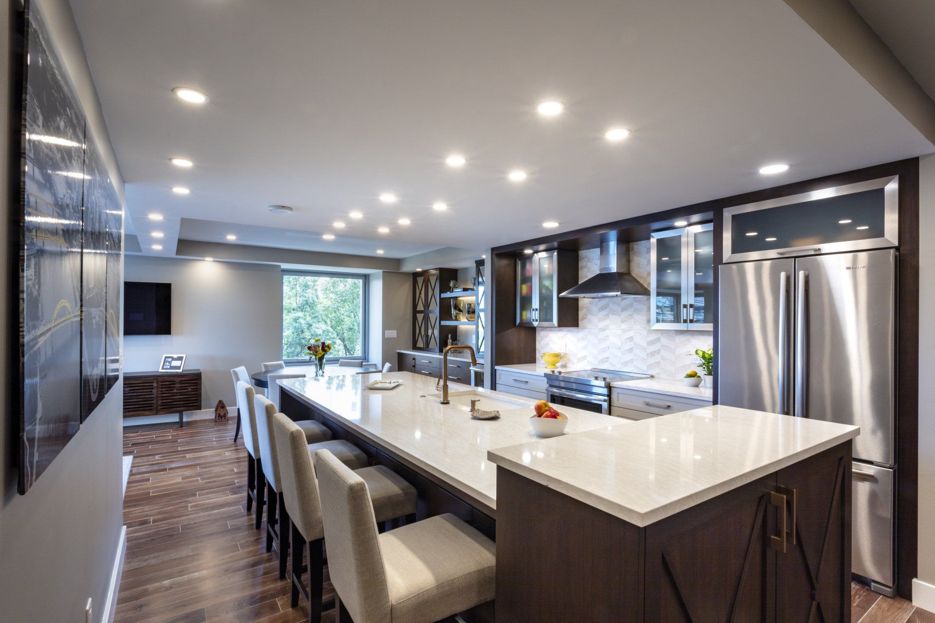 Modern kitchen with marble island, bar stools, stainless steel appliances, and recessed ceiling lights