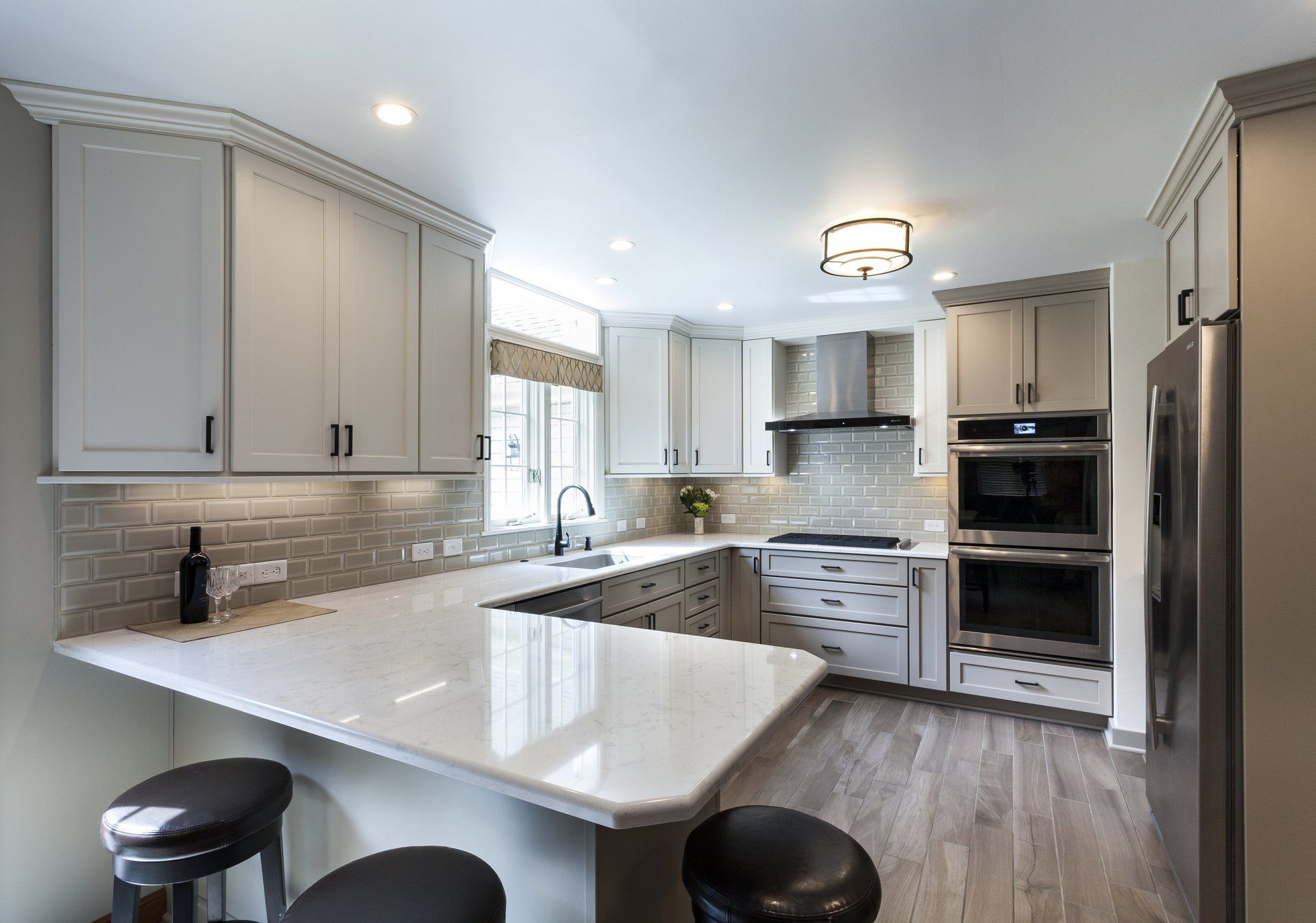 Bright modern kitchen with white cabinets, island, stainless appliances, and wood flooring.