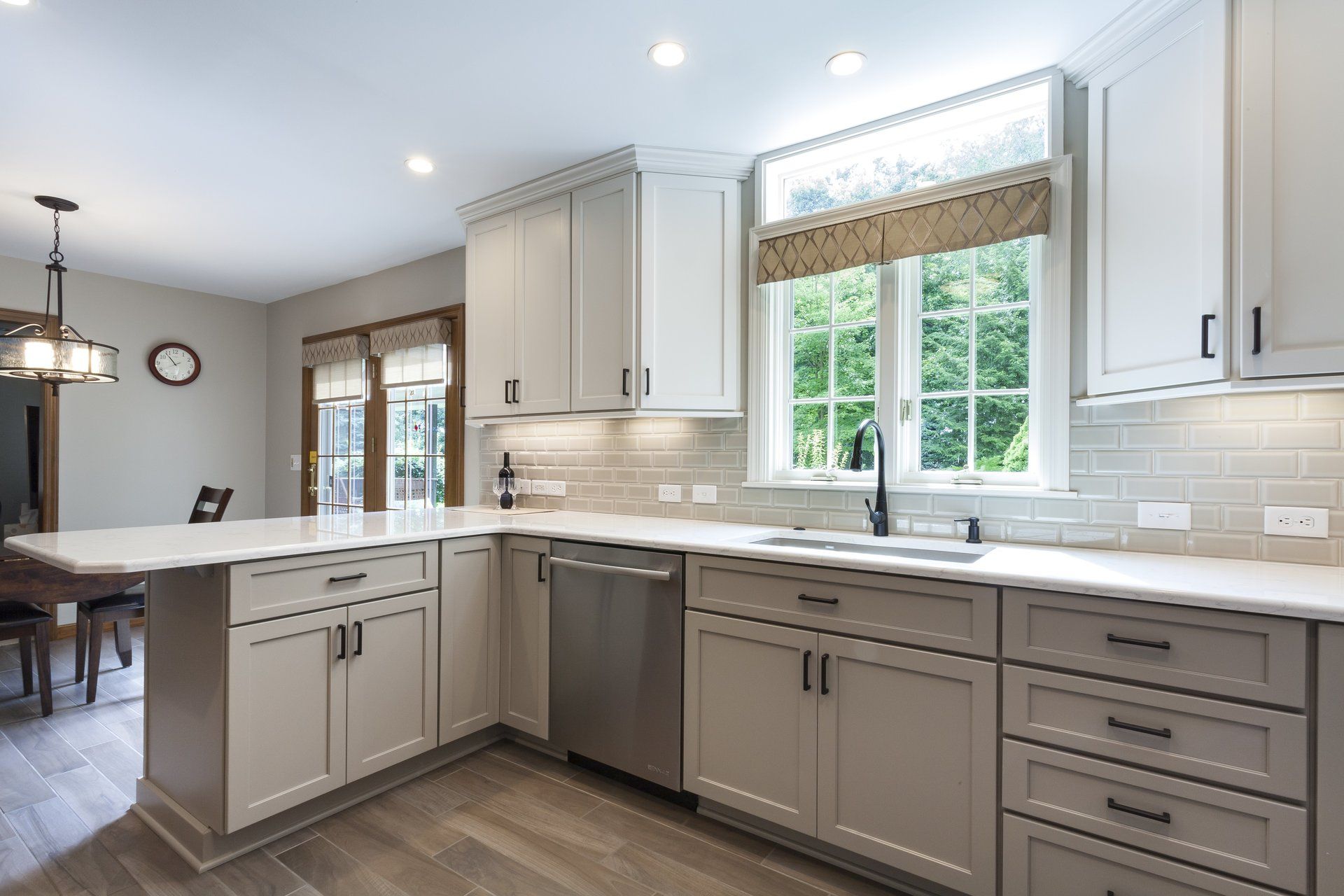 Modern kitchen with gray cabinets, white countertops, stainless appliances, and a window above the sink
