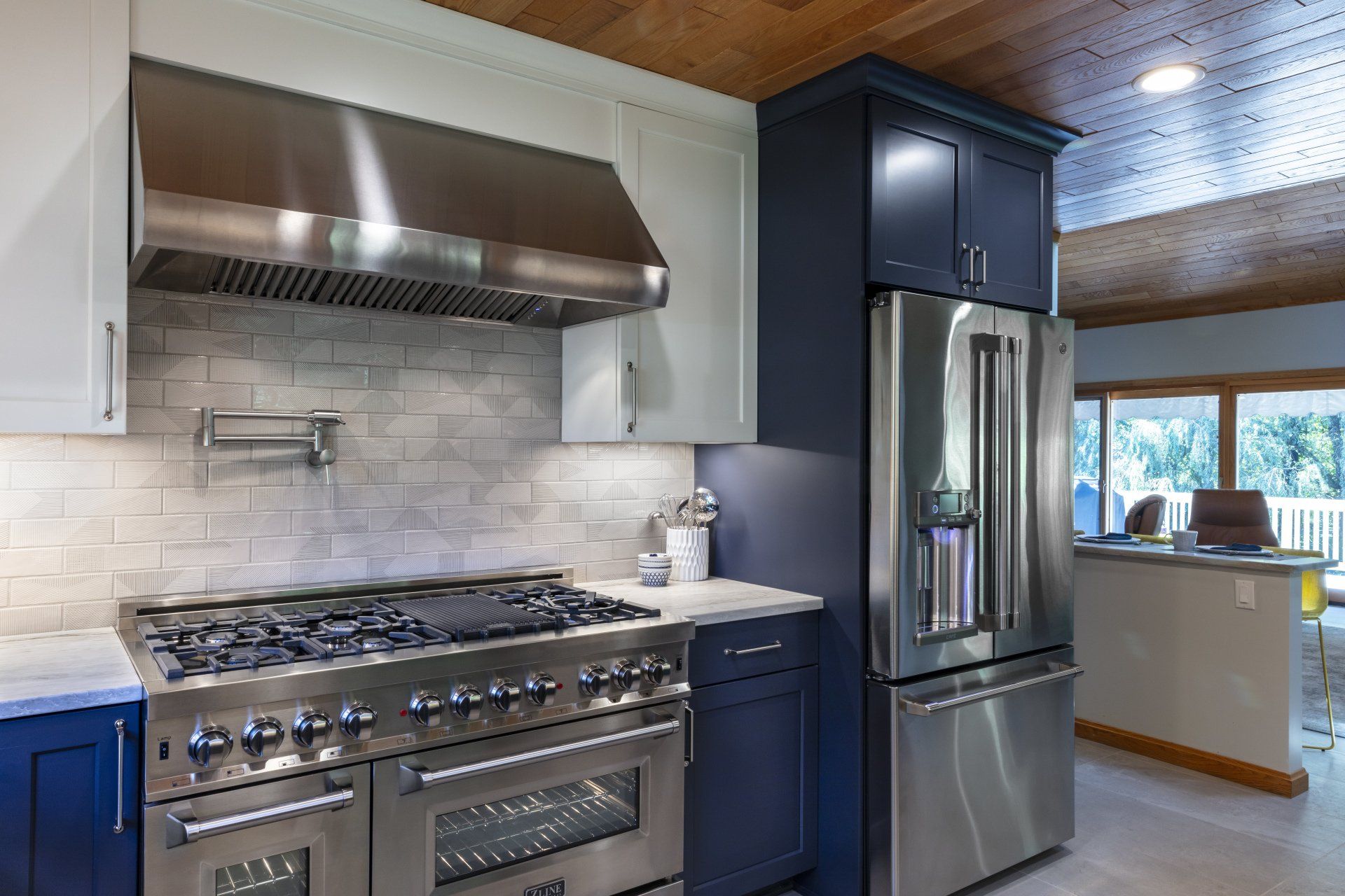 Modern kitchen with stainless steel stove and refrigerator, blue cabinets, and marble backsplash