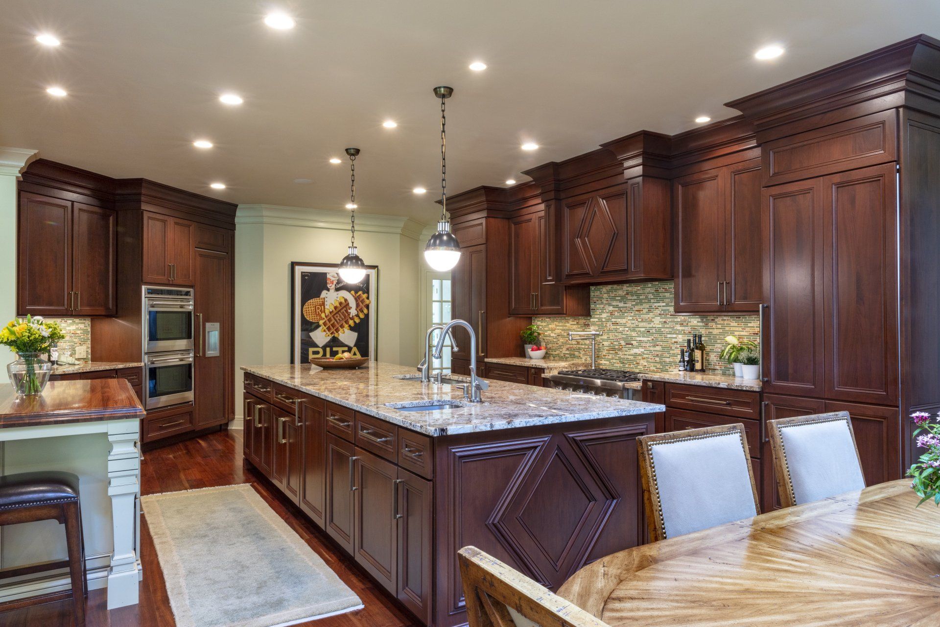 Elegant kitchen with dark wood cabinets, large marble island, pendant lights, and dining table