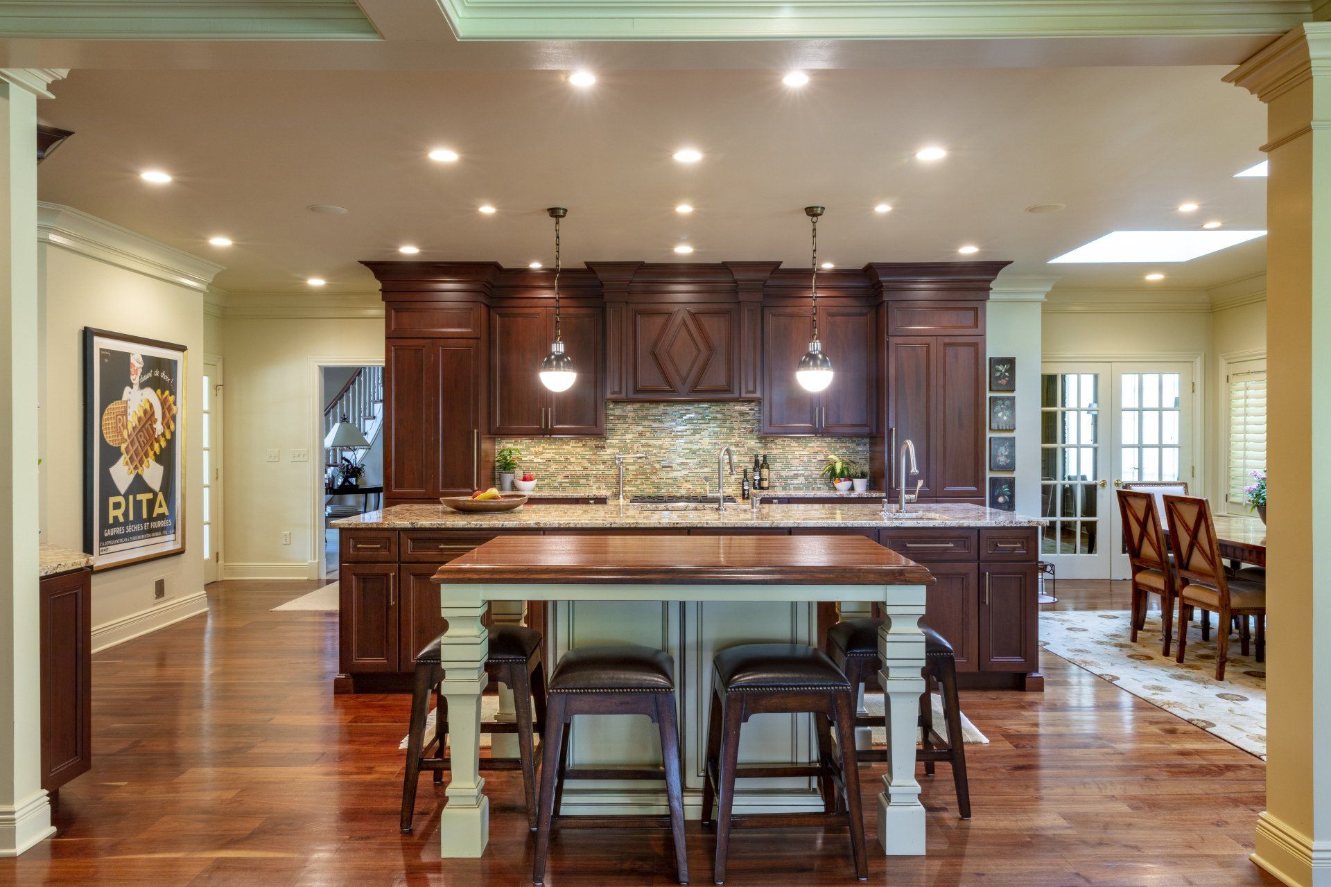 Spacious modern kitchen with dark wood cabinets, central island, and bar stools under recessed lighting
