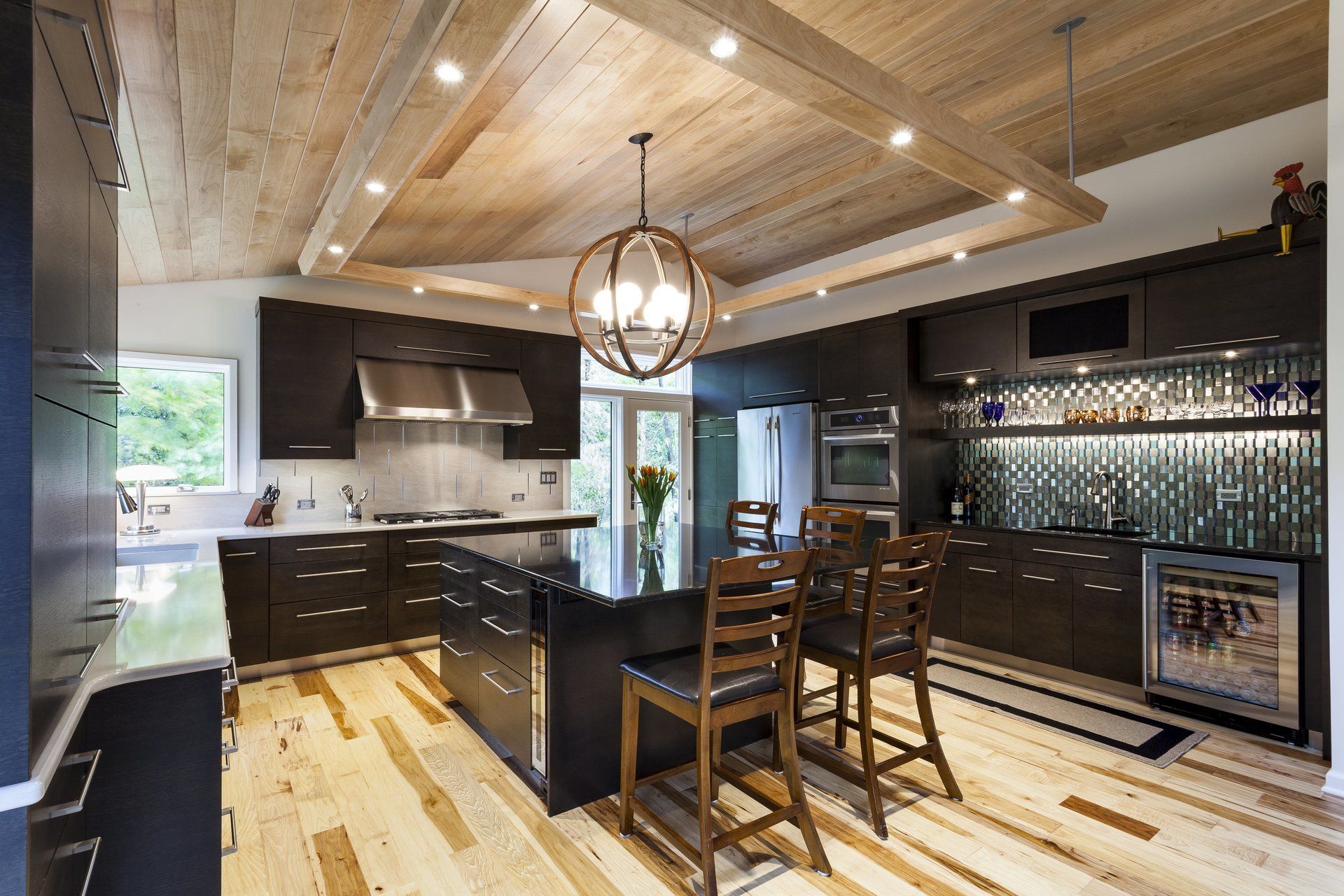 Modern kitchen with black cabinets, island seating, wood ceiling, and mirrored backsplash