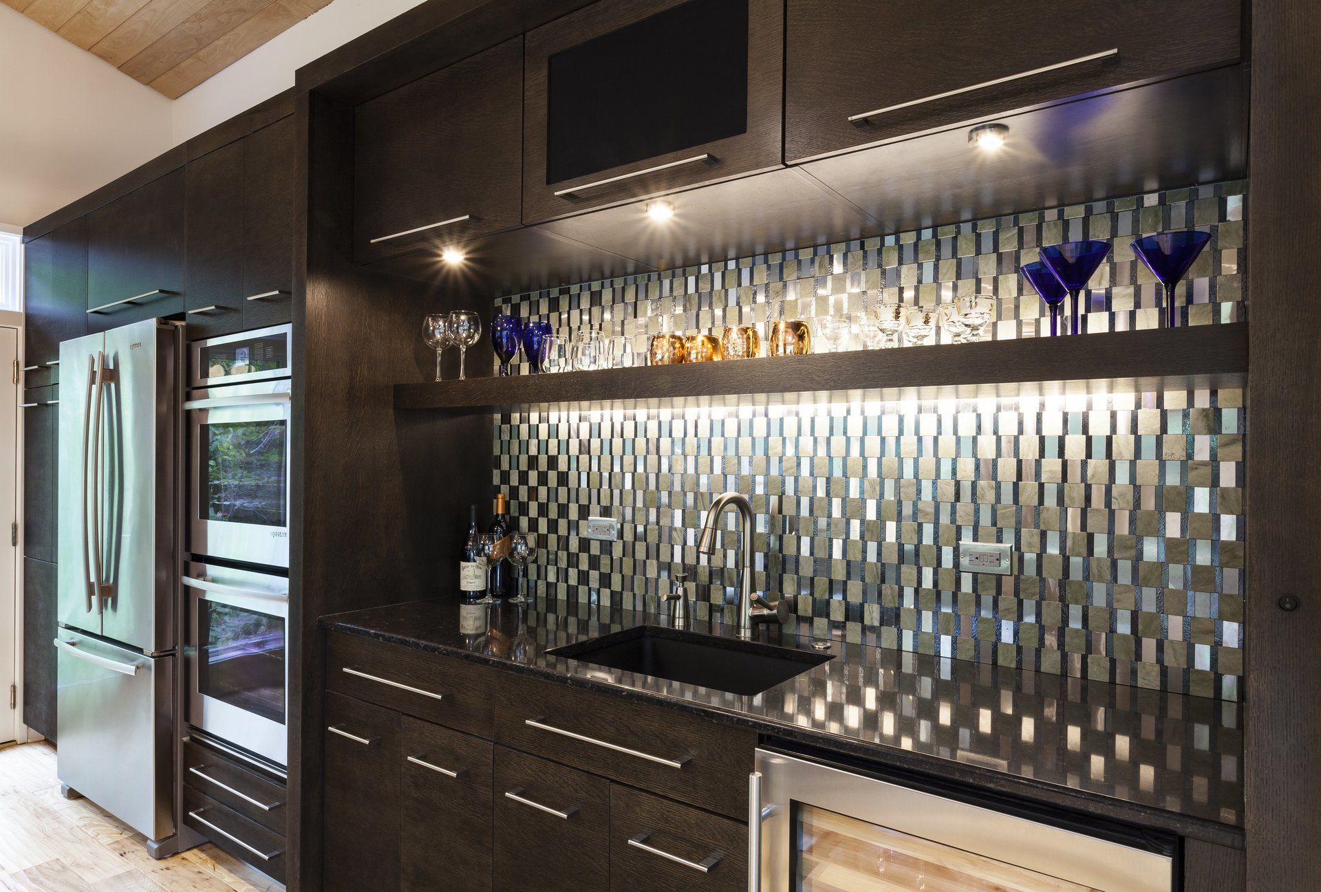 Modern kitchen bar with dark cabinets, mosaic tile backsplash, and built-in wine fridge