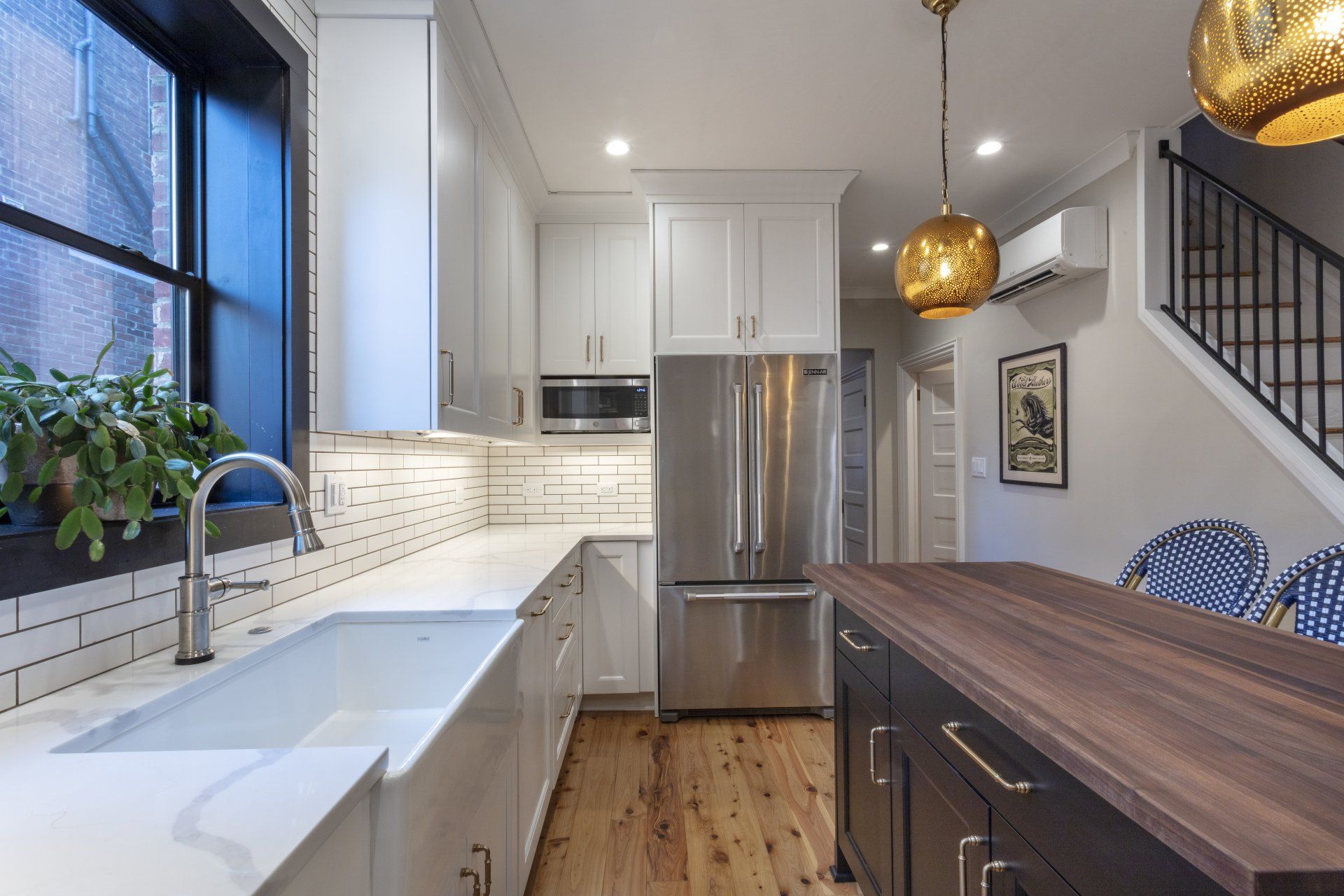 Modern kitchen with stainless steel appliances, white cabinets, wood island, and large window over sink