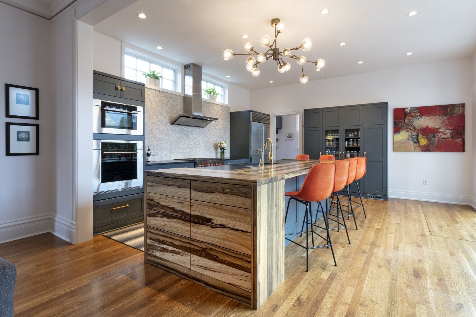Modern kitchen with island, granite countertops, orange bar stools, and hardwood floors