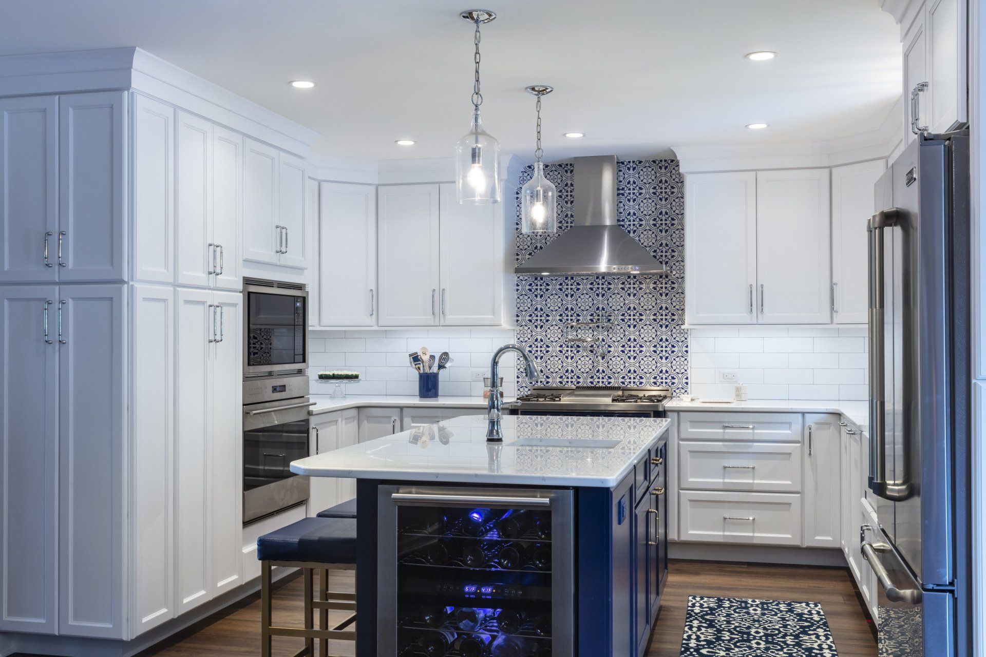 Bright modern white kitchen with island, stainless appliances, pendant lights, and mosaic tile backsplash