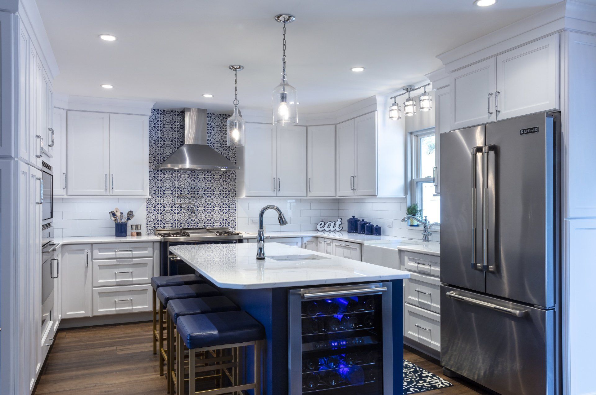 Bright modern kitchen with white cabinets, stainless steel appliances, and a marble island with blue stools