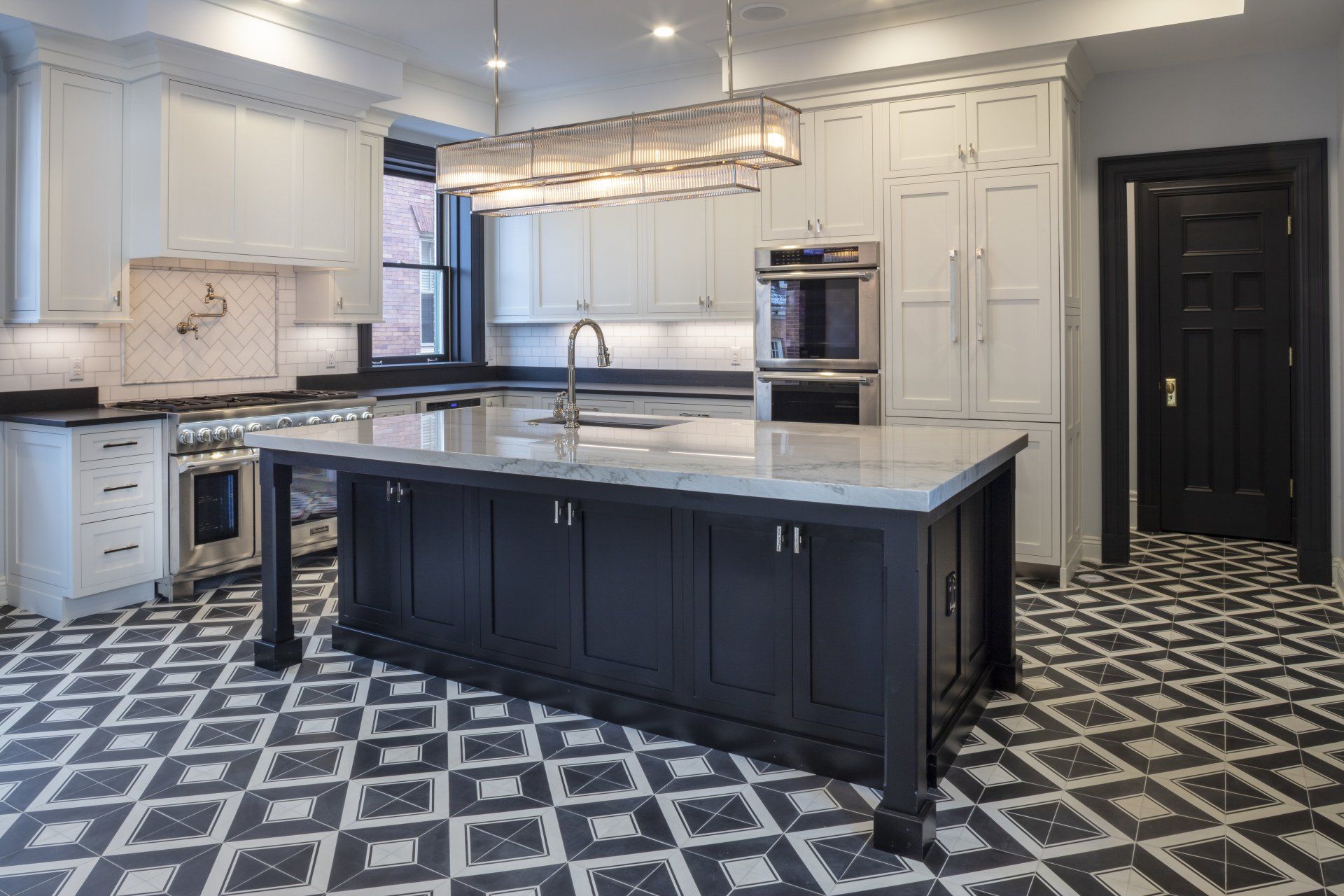 Modern kitchen with white cabinets, black island, and patterned black-and-white tile floor