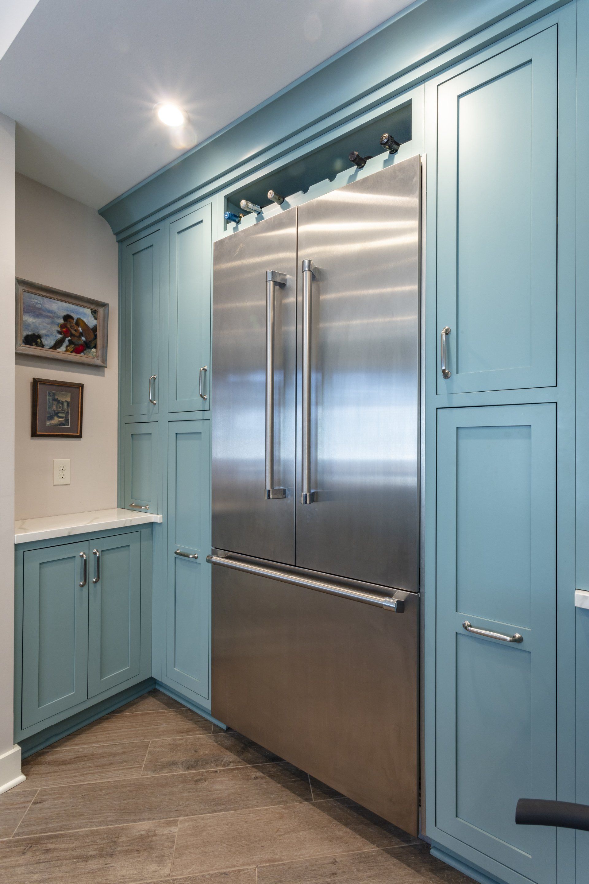 Built-in stainless steel refrigerator surrounded by light blue kitchen cabinets