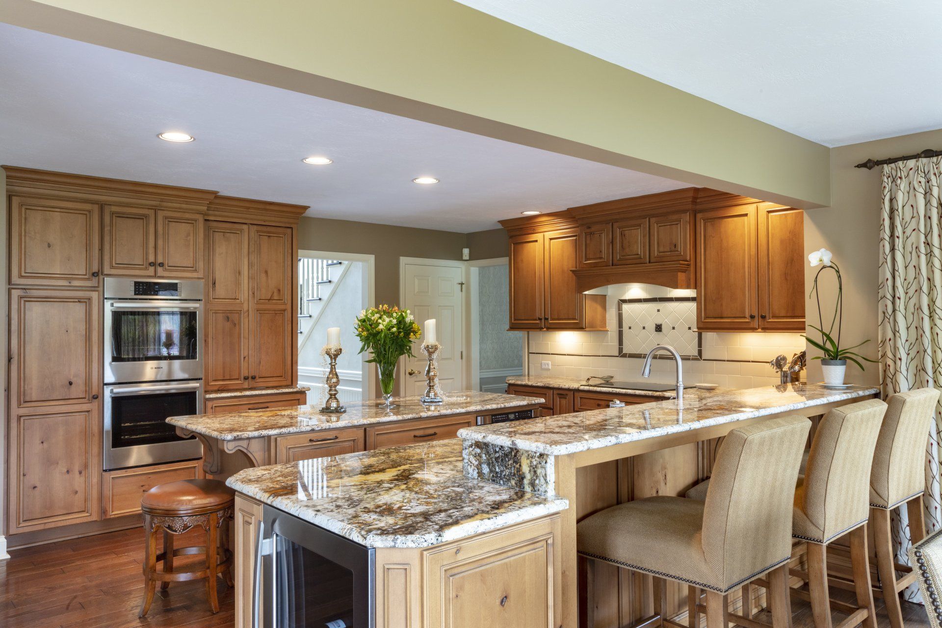 Bright modern kitchen with wood cabinets, granite island, and bar stools under recessed lighting