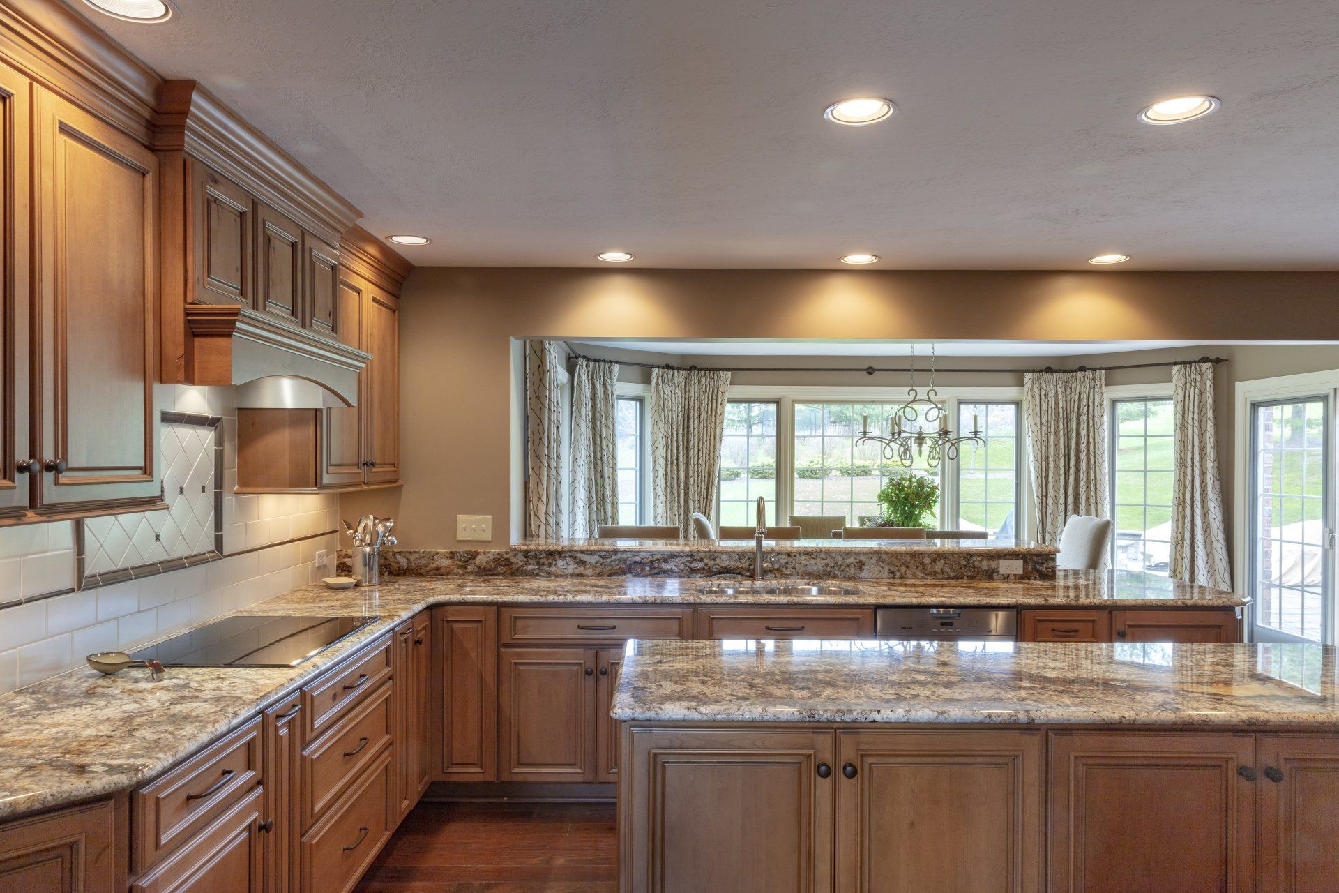 Spacious kitchen with wooden cabinets, granite countertops, and a large center island by bright windows.